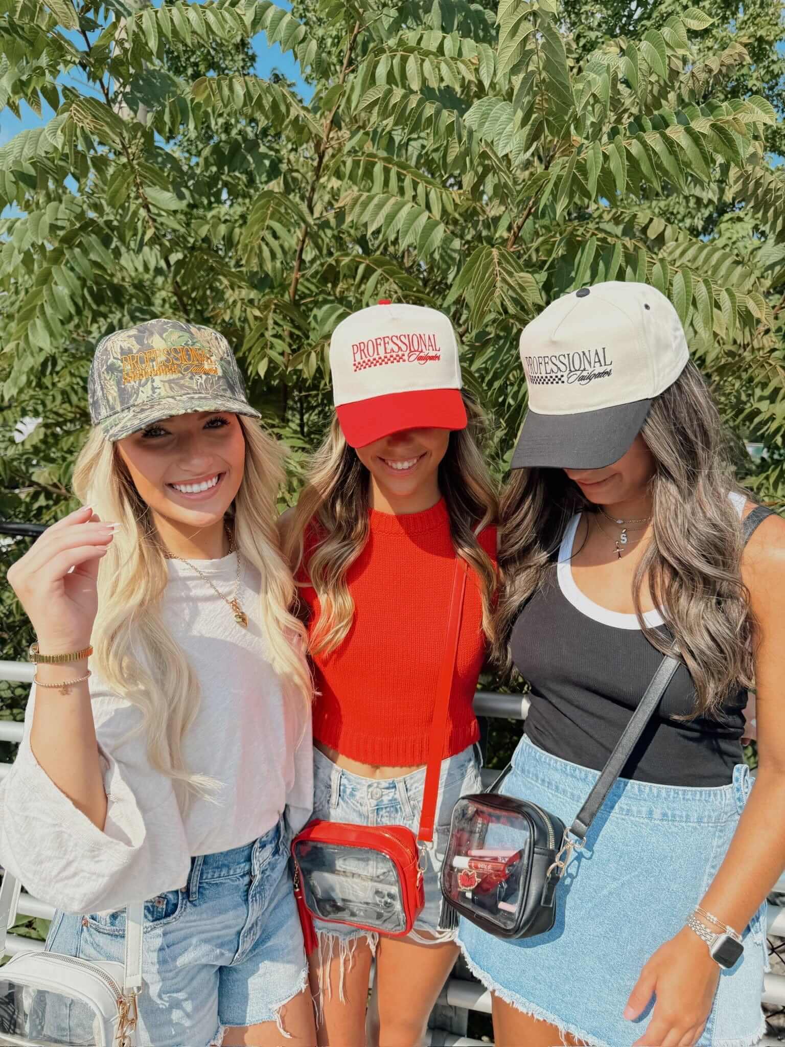 Three women wearing vintage trucker hats in cream, red, and gray with "Professional Tailgater" text visible on the brims.
