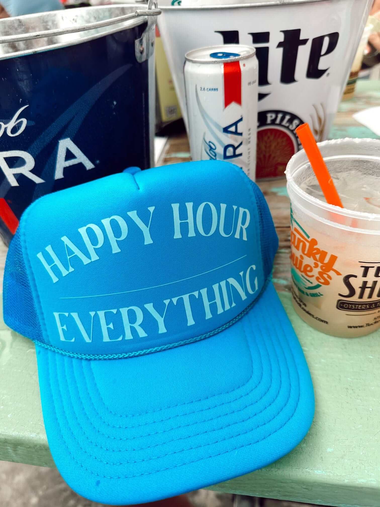 Bright blue trucker hat with "Happy Hour Everything" text in white across the front.