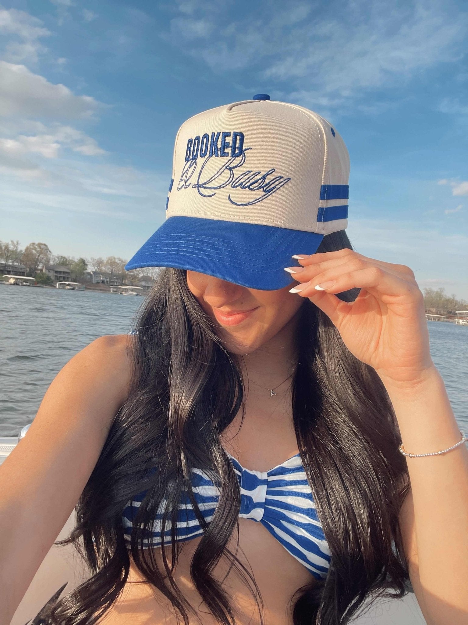 Cream and royal blue vintage trucker hat with "Booked and Busy" text and striped detail on the crown.