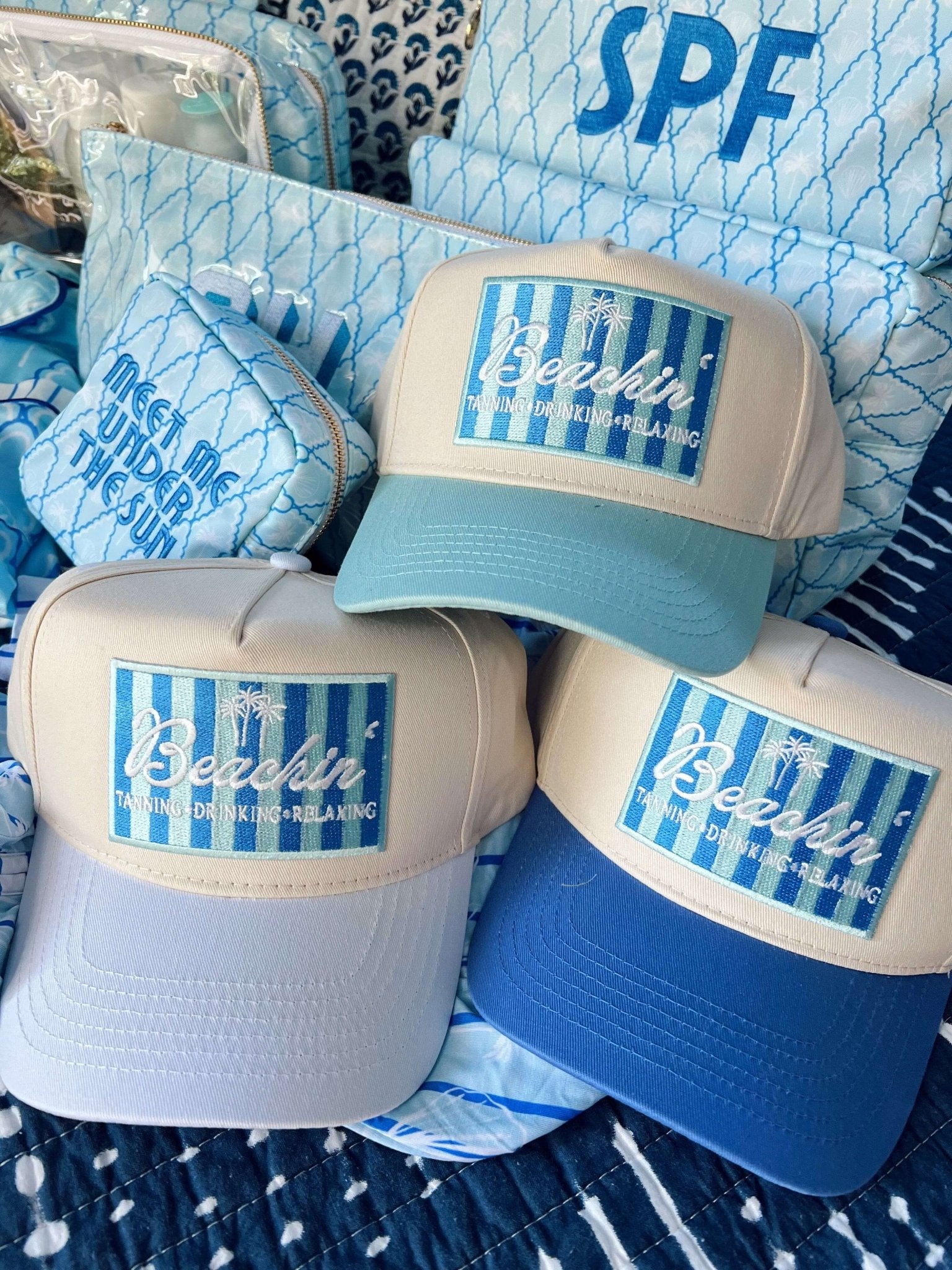 Three vintage trucker hats with blue and white colorblocking featuring "Beachin'" text and striped design patches.