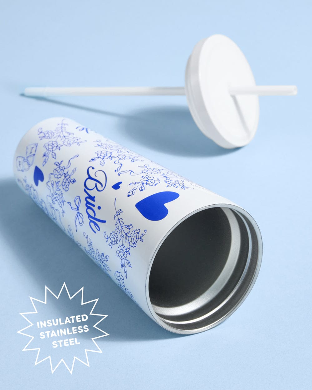 White insulated tumbler with blue heart and "Something Blue" text, stainless steel construction, shown with matching white lid and straw on blue background.
