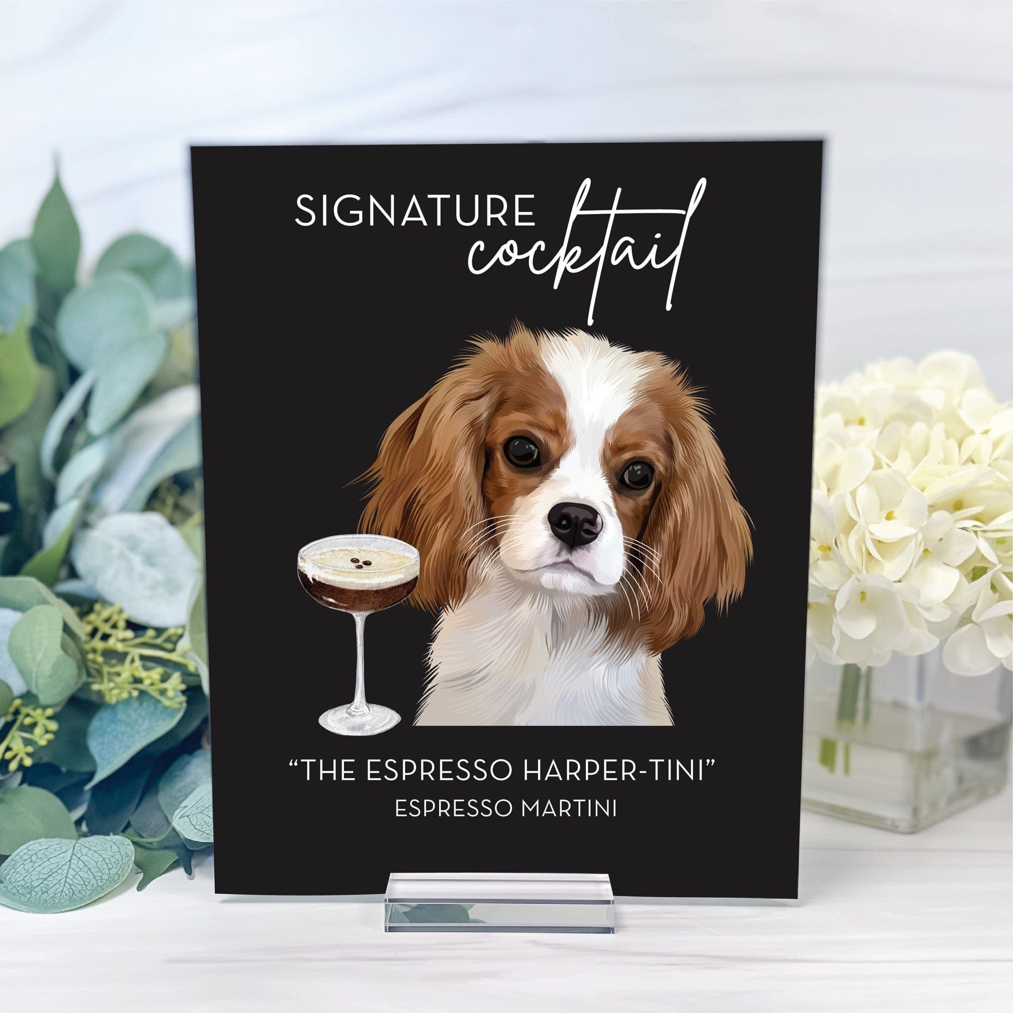 A personalized black signature cocktail sign features a charming illustration of a brown and white dog beside an espresso martini, elegantly displayed on a clear acrylic stand for wedding or event bar decor.