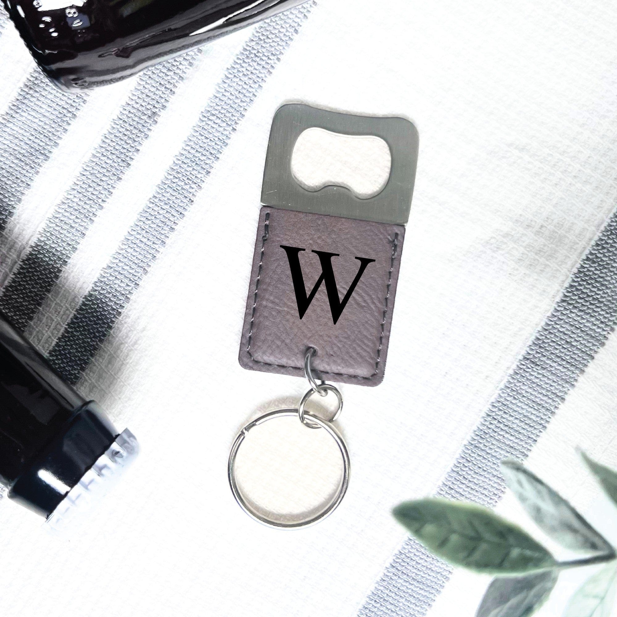 A single brown leatherette keychain featuring a silver metal bottle opener and a split key ring, designed for functionality as a personalized gift or event favor.