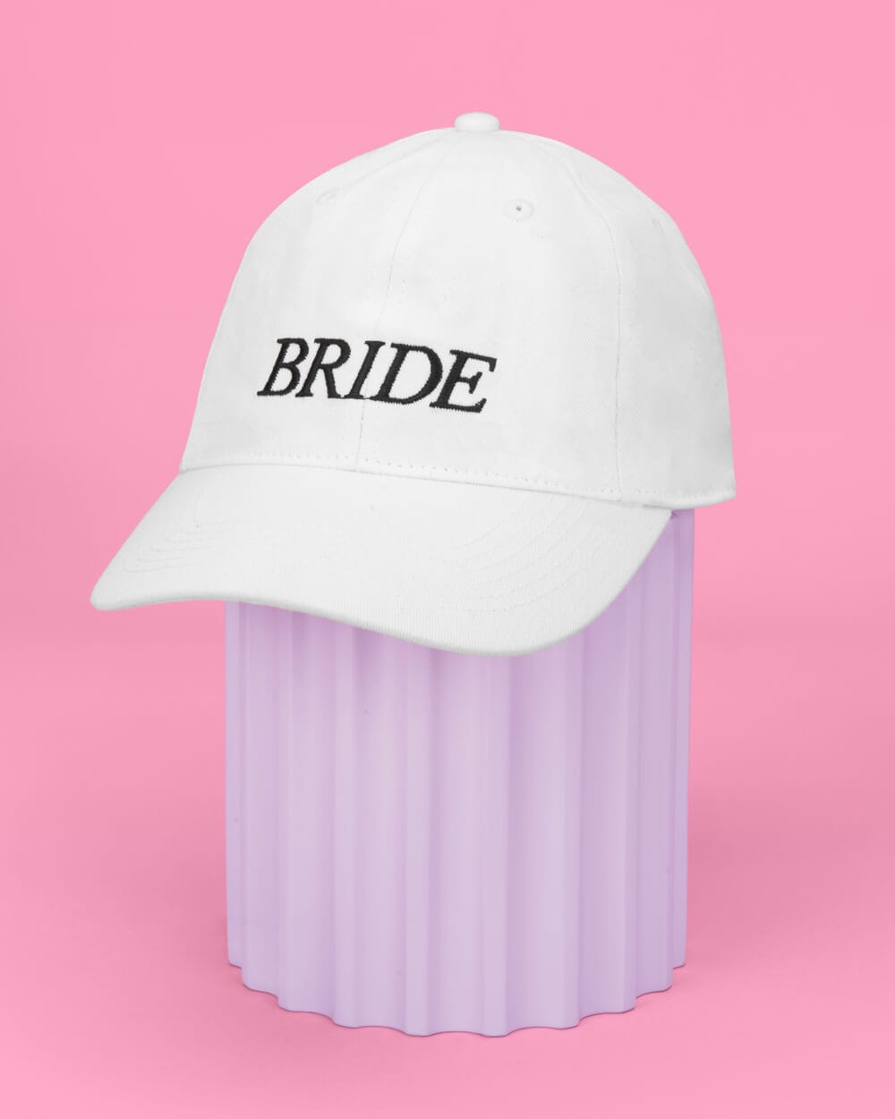 White baseball cap embroidered with "BRIDE" text on pink background