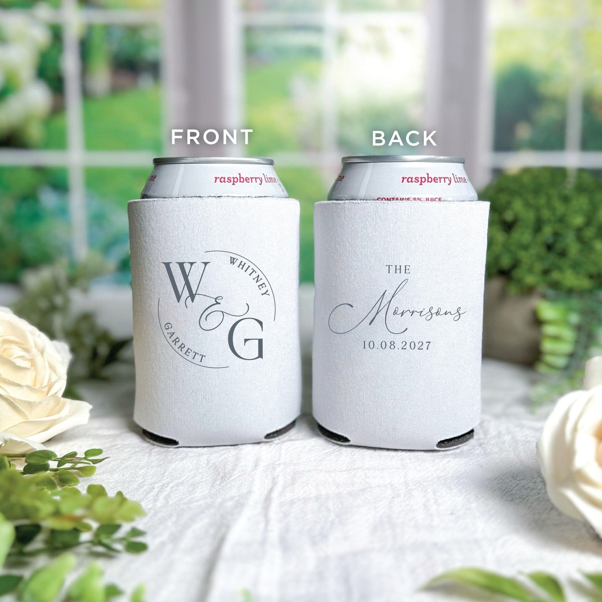 Two white neoprene can coolers, personalized with elegant dark grey designs, are displayed for a wedding event, one featuring a stylized initial monogram and the other a graceful script family name.
