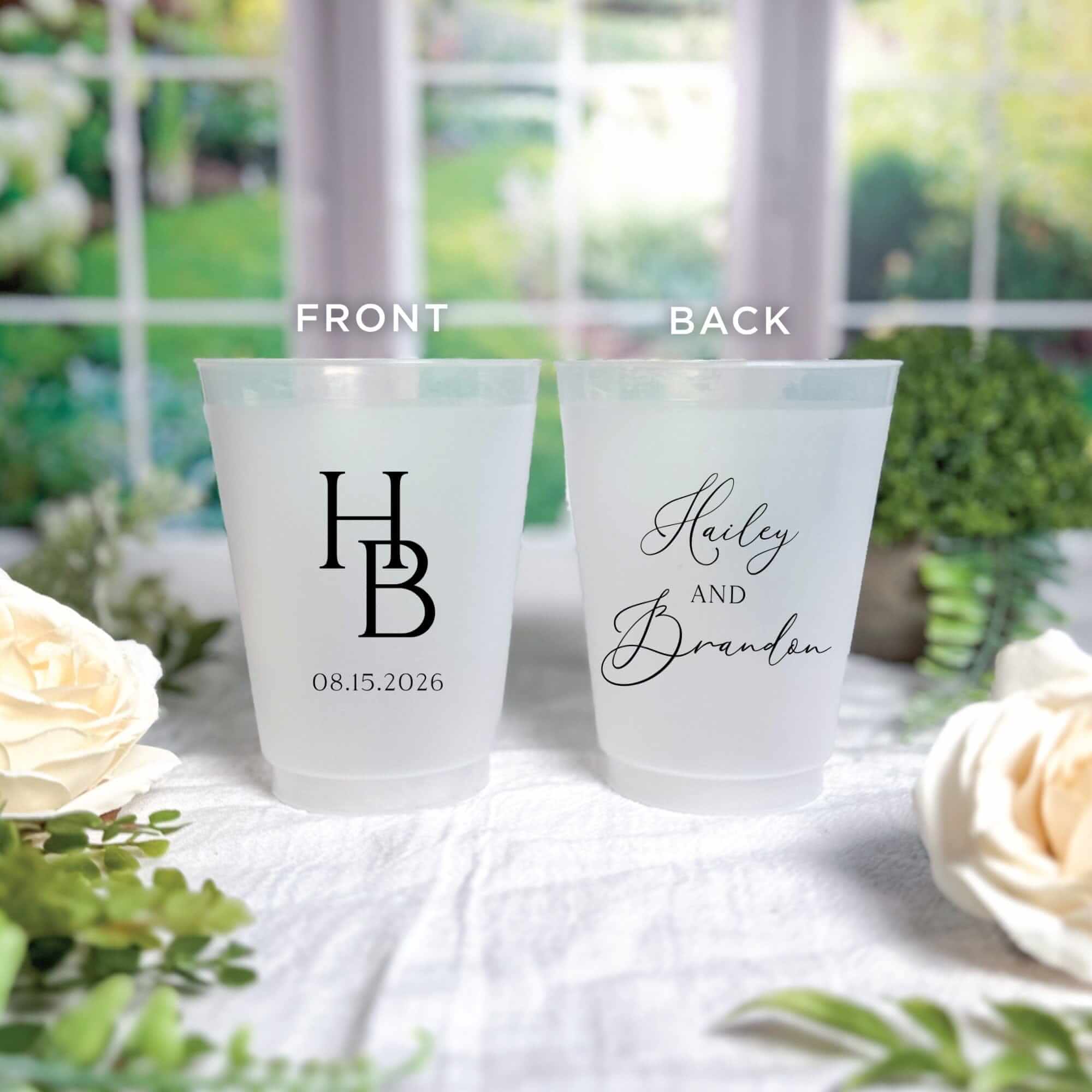 Two personalized frosted translucent plastic cups, ideal for a wedding, showcasing a custom monogram on the front and elegant script text on the back.