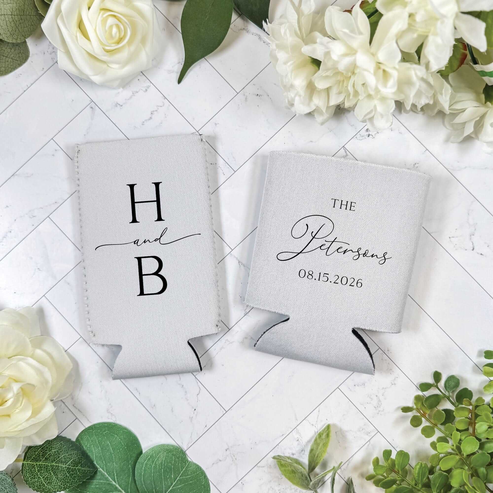 Two white neoprene can coolers, custom-designed with a wedding theme to keep beverages cool for guests.