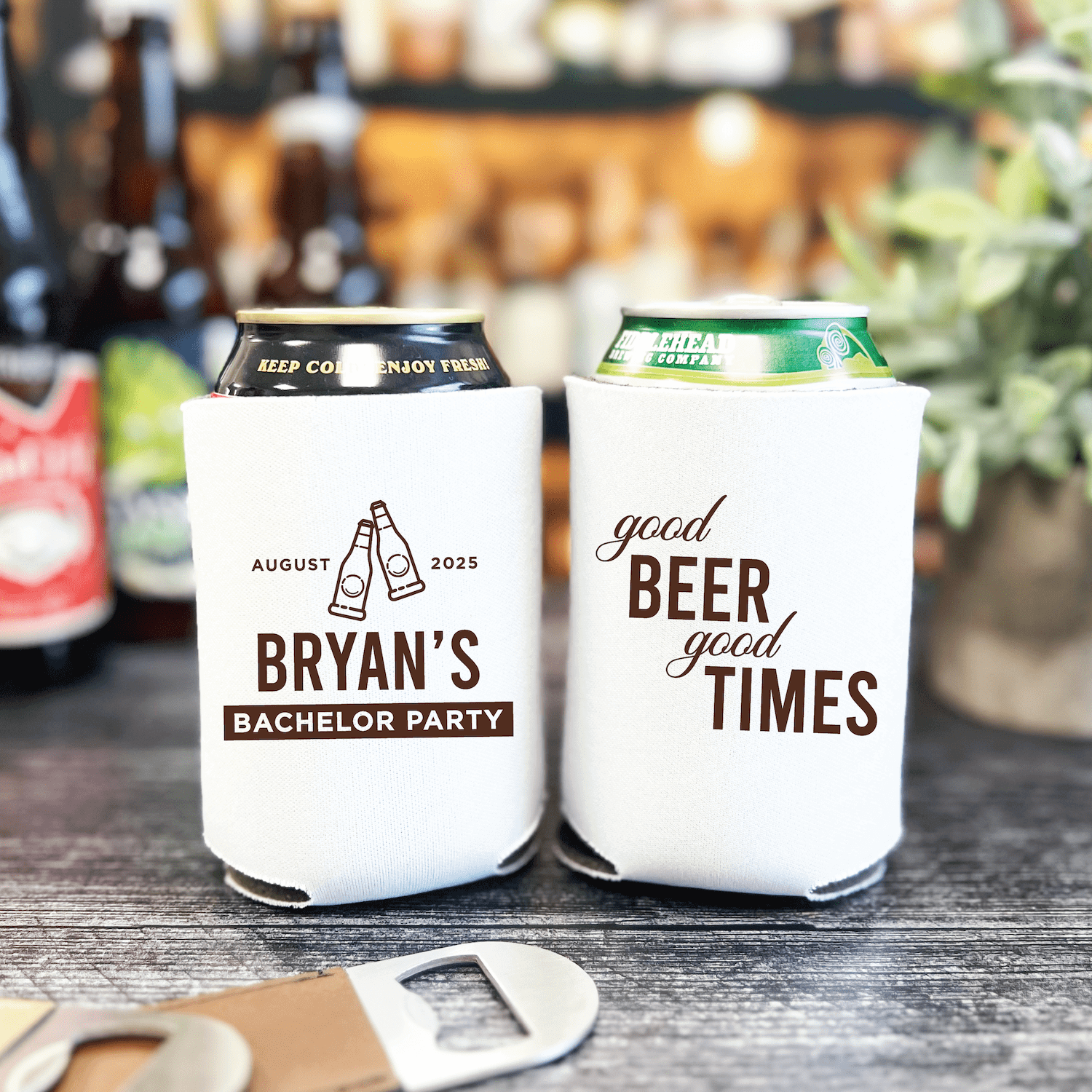 White can coolers with black text, one reading "Bryan's Bachelor Party August 2025" with champagne design, the other "good beer good times"