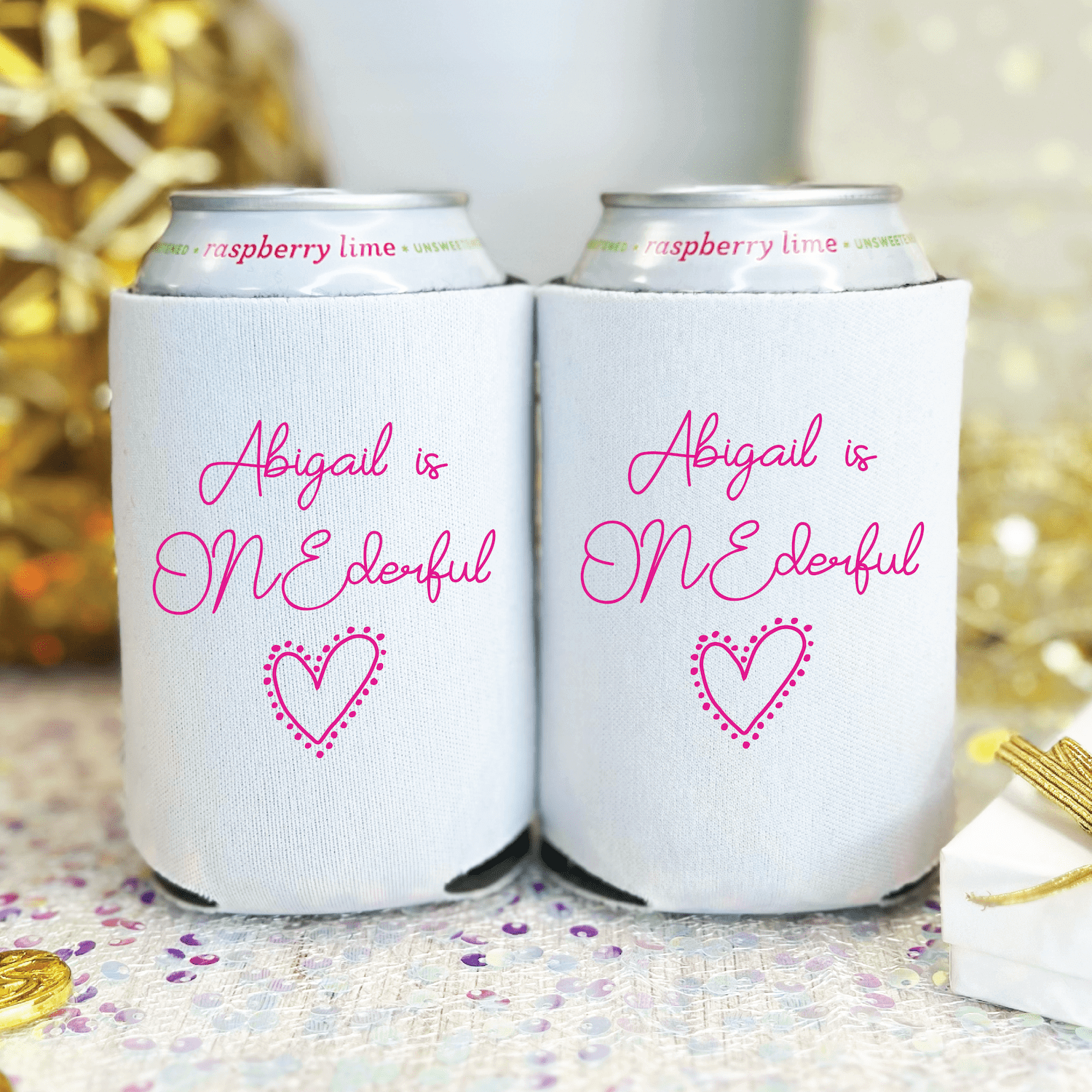 White can coolers with hot pink text reading "Abigail is ONE derful" and a dotted heart design, personalized for a first birthday celebration.