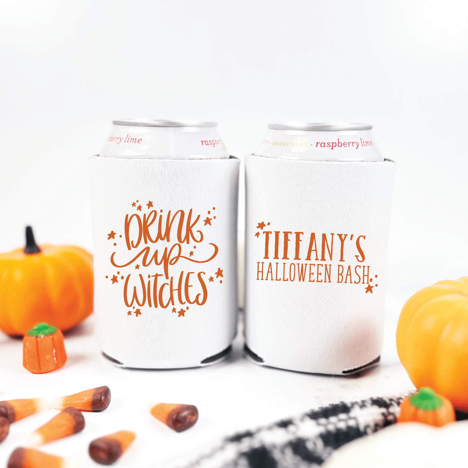 Two white can coolers with orange Halloween designs: one reads "drink up witches" with sparkles, the other says "Tiffany's Halloween Bash" surrounded by pumpkins and fall decorations.
