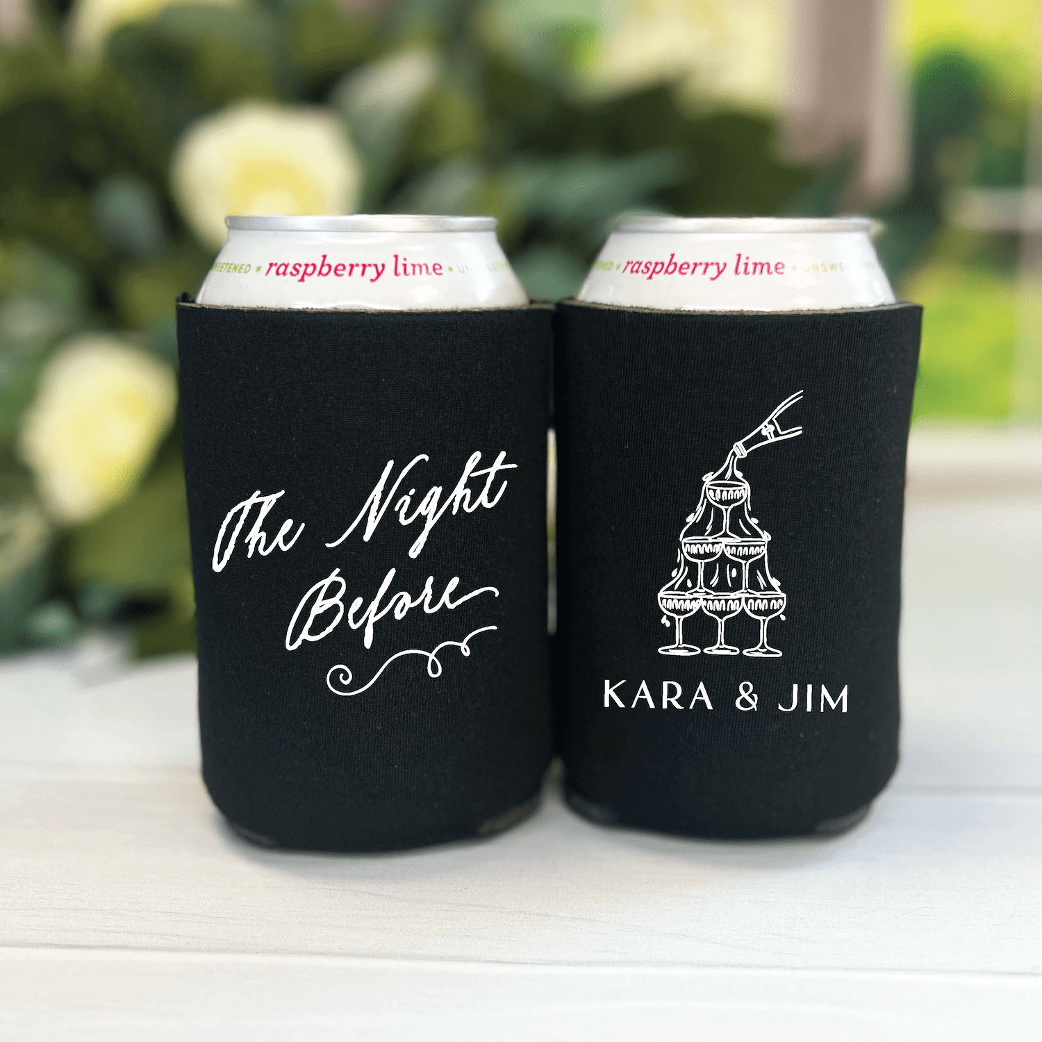 Black neoprene can coolers with "The Night Before" script and tiered cake design with "KARA & JIM" personalization, holding raspberry lime beverages.