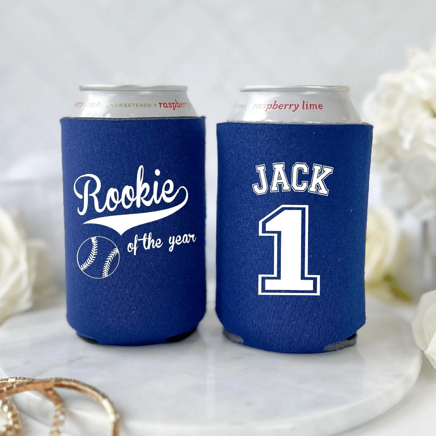 Two blue neoprene can coolers with personalized baseball designs, one reading "Rookie of the year" with baseball icon, the other showing "JACK 1" in sports jersey style.