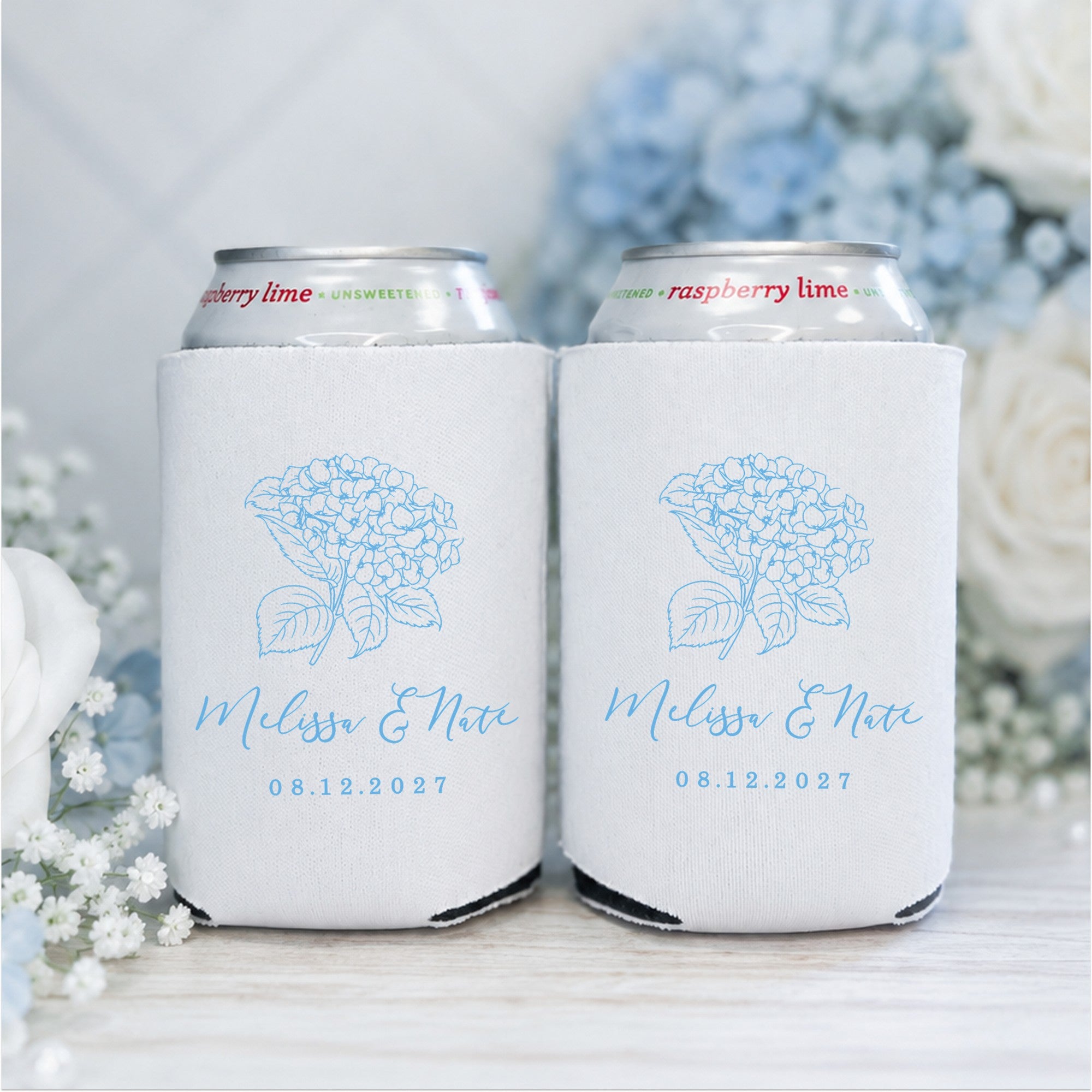 Two white neoprene can coolers designed for a wedding, each featuring a delicate blue hydrangea flower graphic.