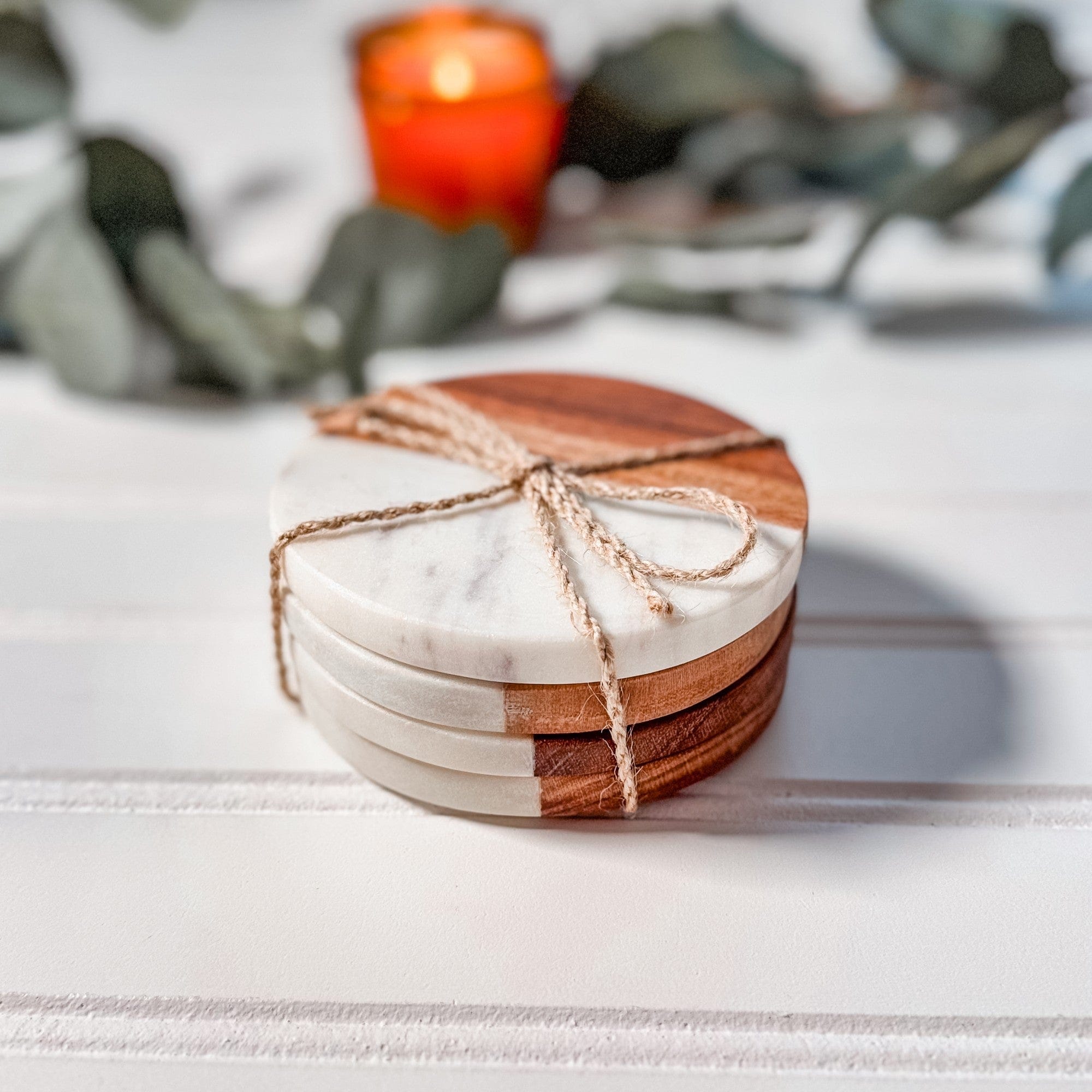 A stack of round coasters crafted from elegant white marble and rich brown wood, tied with natural twine, suitable as wedding favors or event decor.