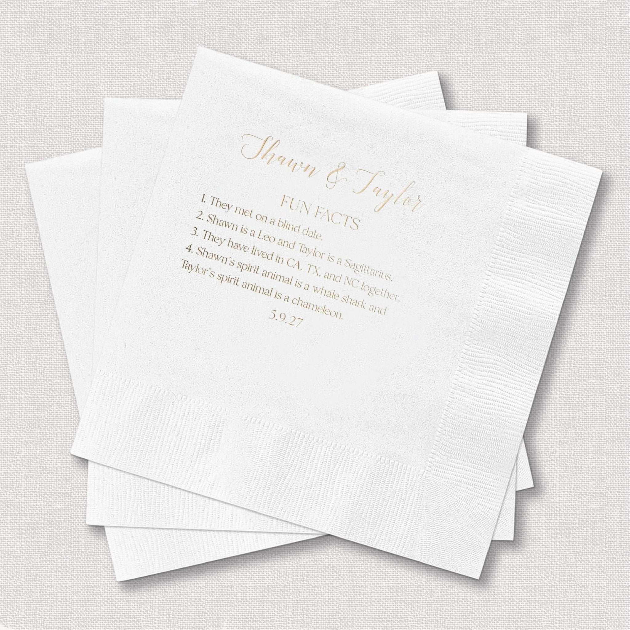 Stack of white napkins with gold foil-stamped couple names and fun facts for wedding reception