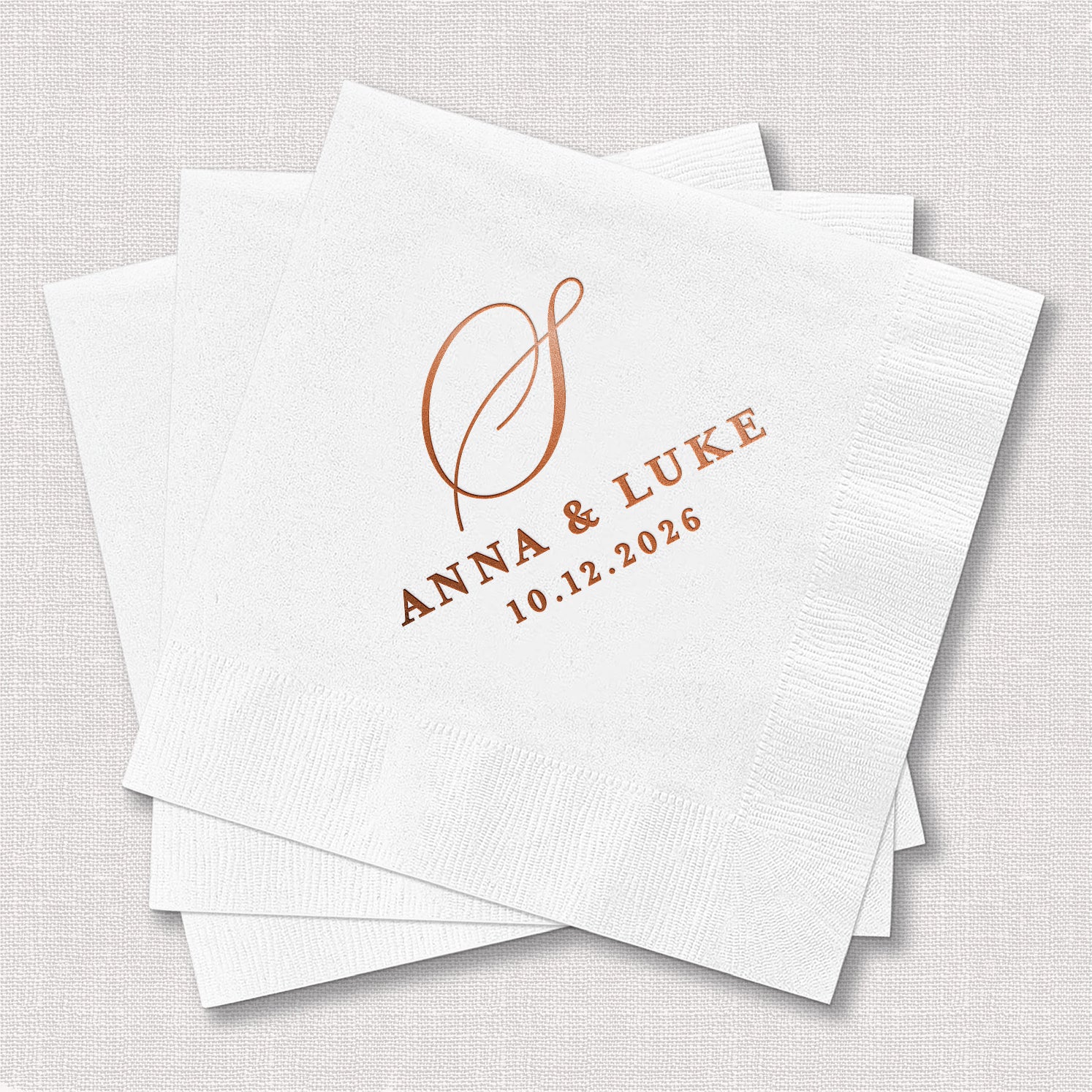 Stack of personalized white cocktail napkins with classic monogram wedding design printed with single initial and couple's names