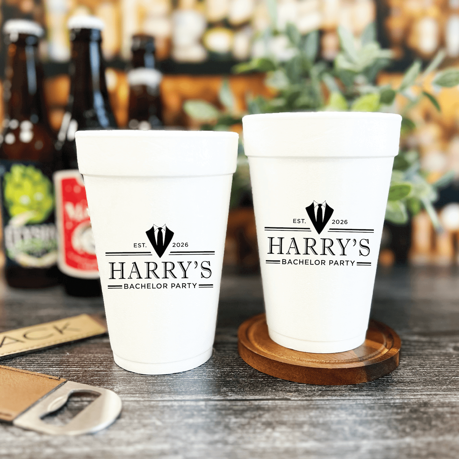 White foam cups personalized with "Harry's Bachelor Party" text and crown design, displayed with beer bottles in background.