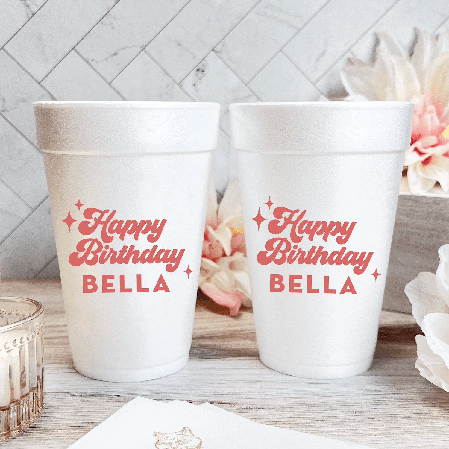 Two white foam cups with pink "Happy Birthday BELLA" text and star design