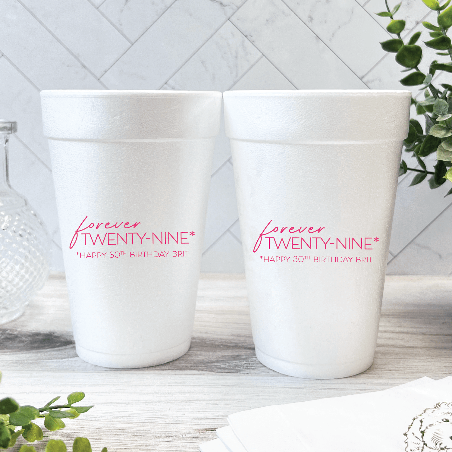 Two white foam cups with pink "Forever Twenty-Nine" text and personalized birthday messages printed on the sides
