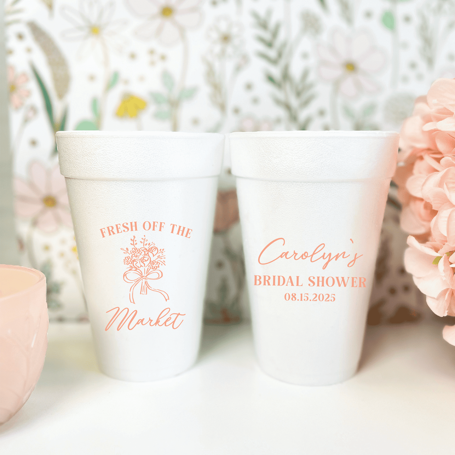 Two white foam cups with coral text, one reading "Fresh Off The Market" with a bouquet design, the other personalized "Carolyn's Bridal Shower 08.15.2023"