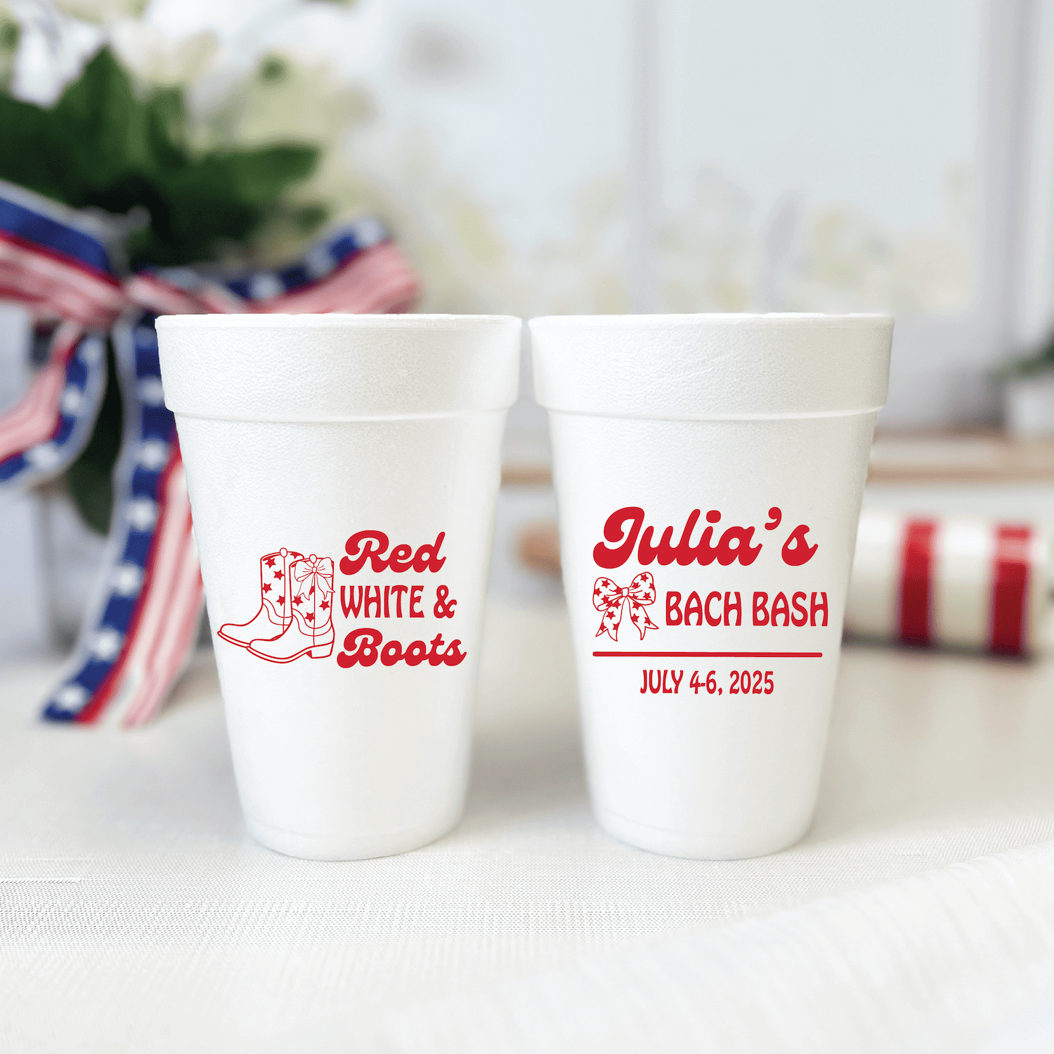 Two white foam cups with red text and cowboy boot design, one reading "Red White & Boots" and the other "Julia's Bach Bash July 4-6, 2025"