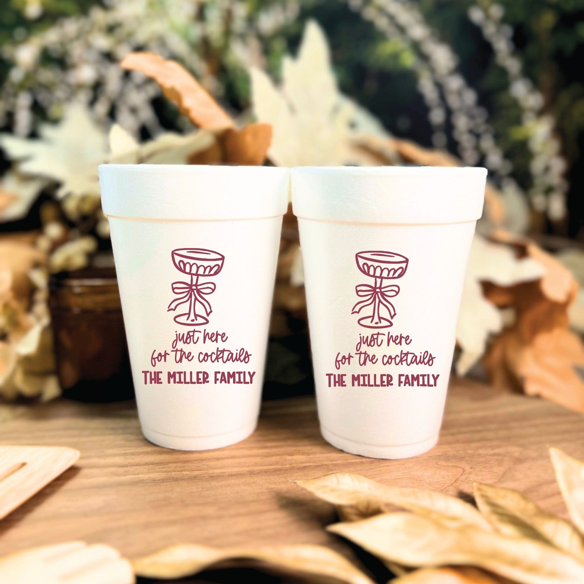 Two white foam cups featuring a custom maroon cocktail glass illustration and personalized text, ideal for serving drinks at a celebratory event.