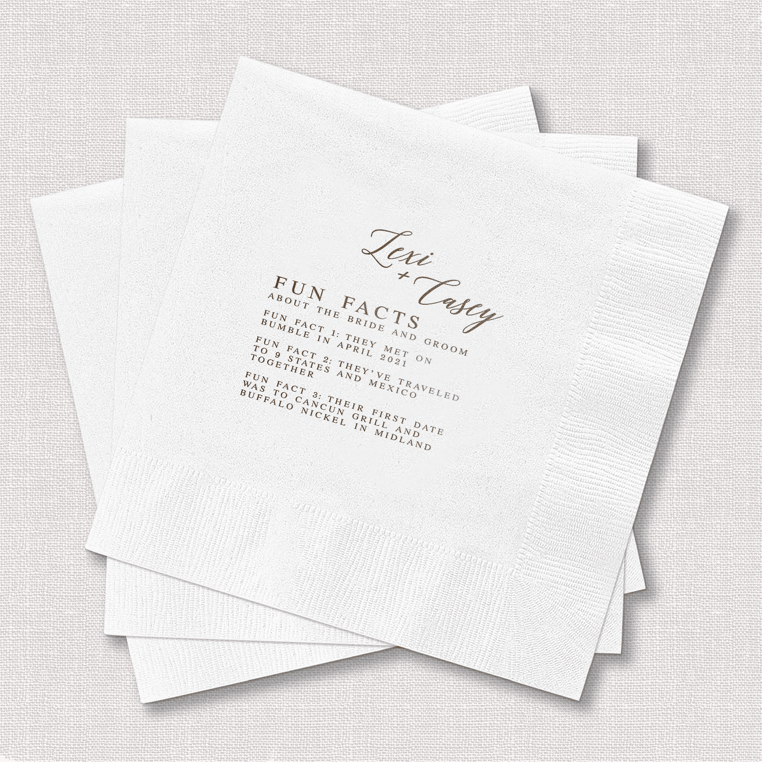 White napkins with foil-stamped "Love Story" heading and fun fact text printed in elegant script and serif fonts.