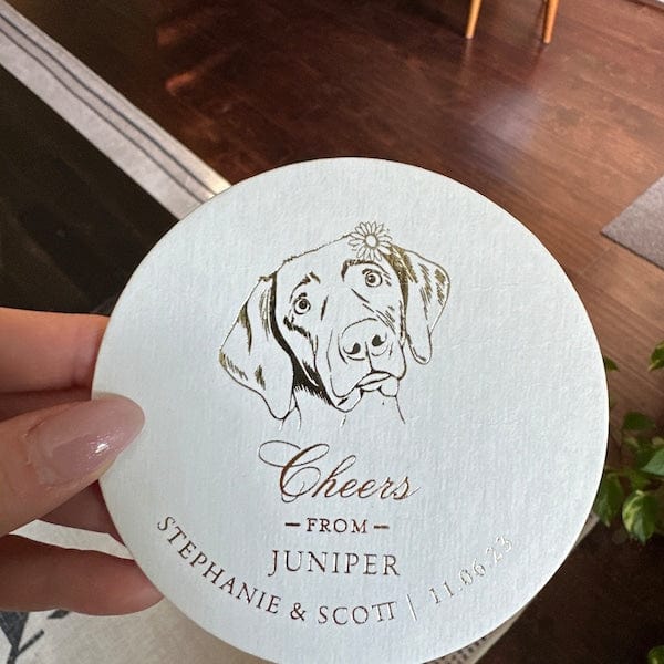 White coaster with dog illustration and "Cheers from Juniper, Stephanie & Scott" personalization text