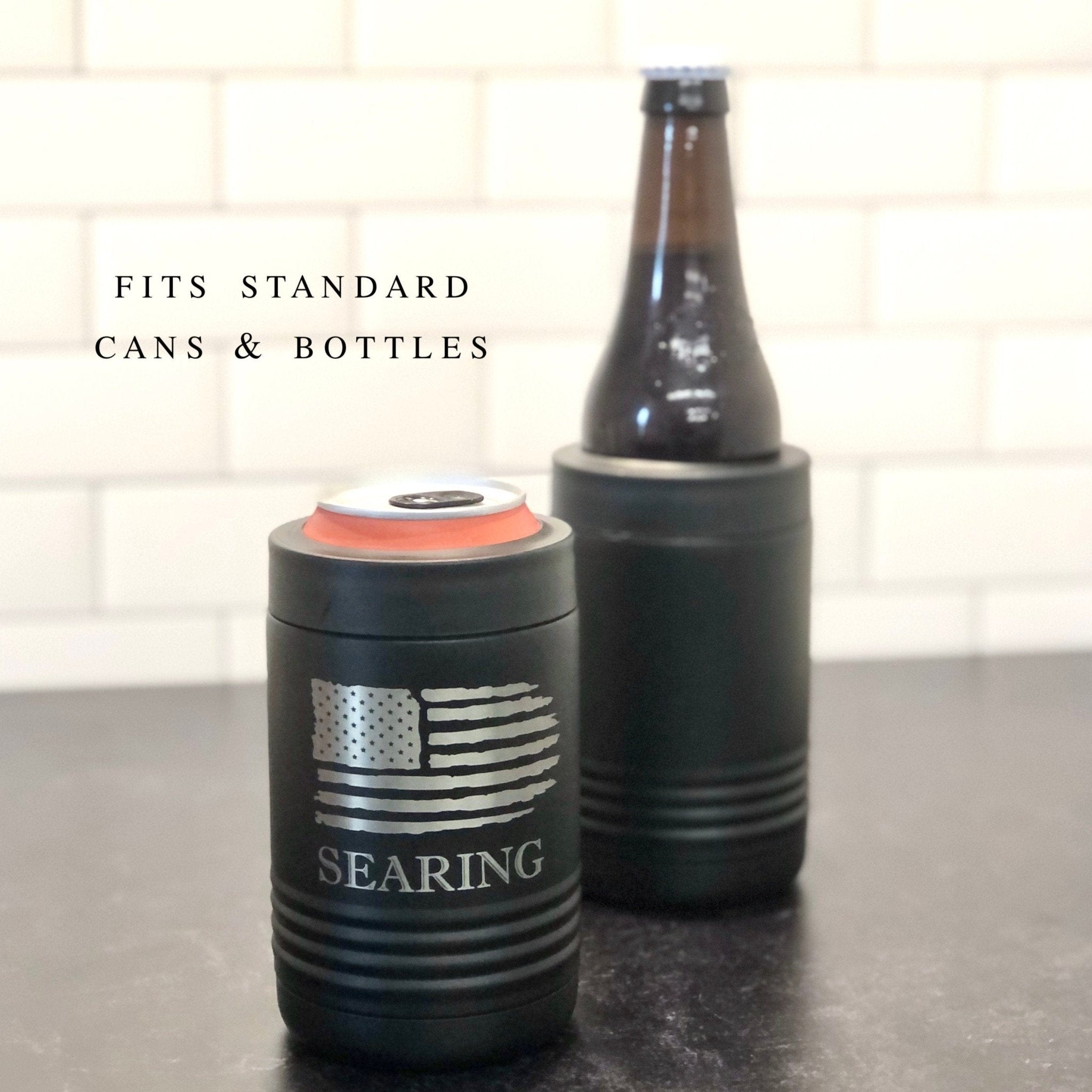 Black metal can cooler with American flag design and "SEARING" text, shown next to beer bottle with matching black cooler
