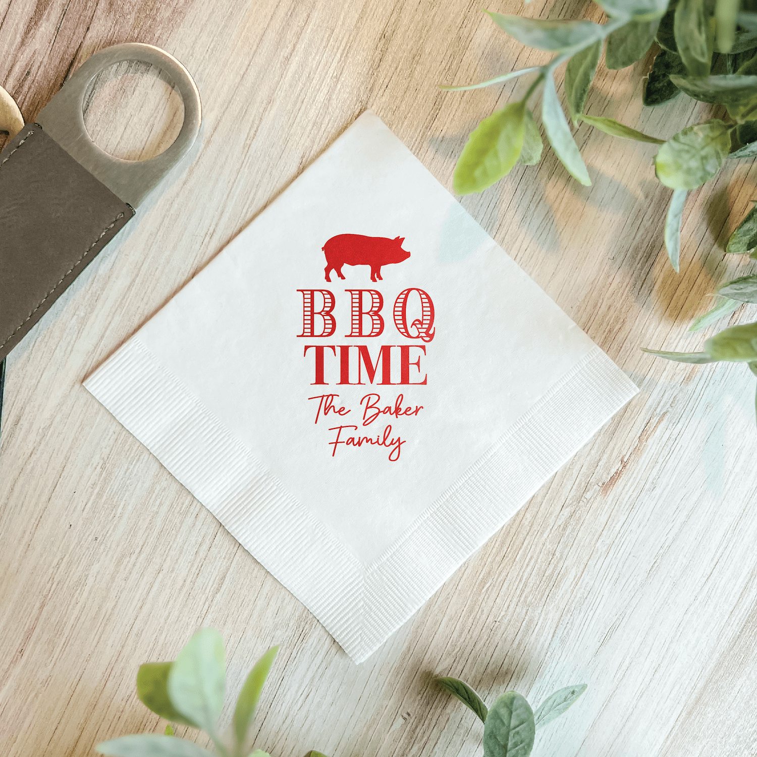 White napkin with red foil stamped BBQ pig design and "BBQ TIME The Baker Family" text