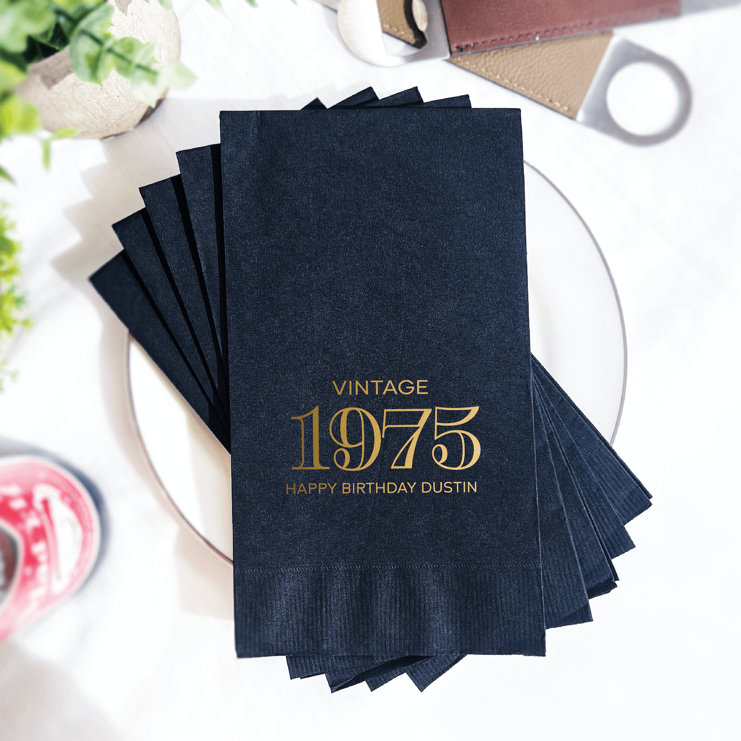 Stack of navy blue napkins with gold foil stamped text reading "Vintage 1975 Happy Birthday Dustin"