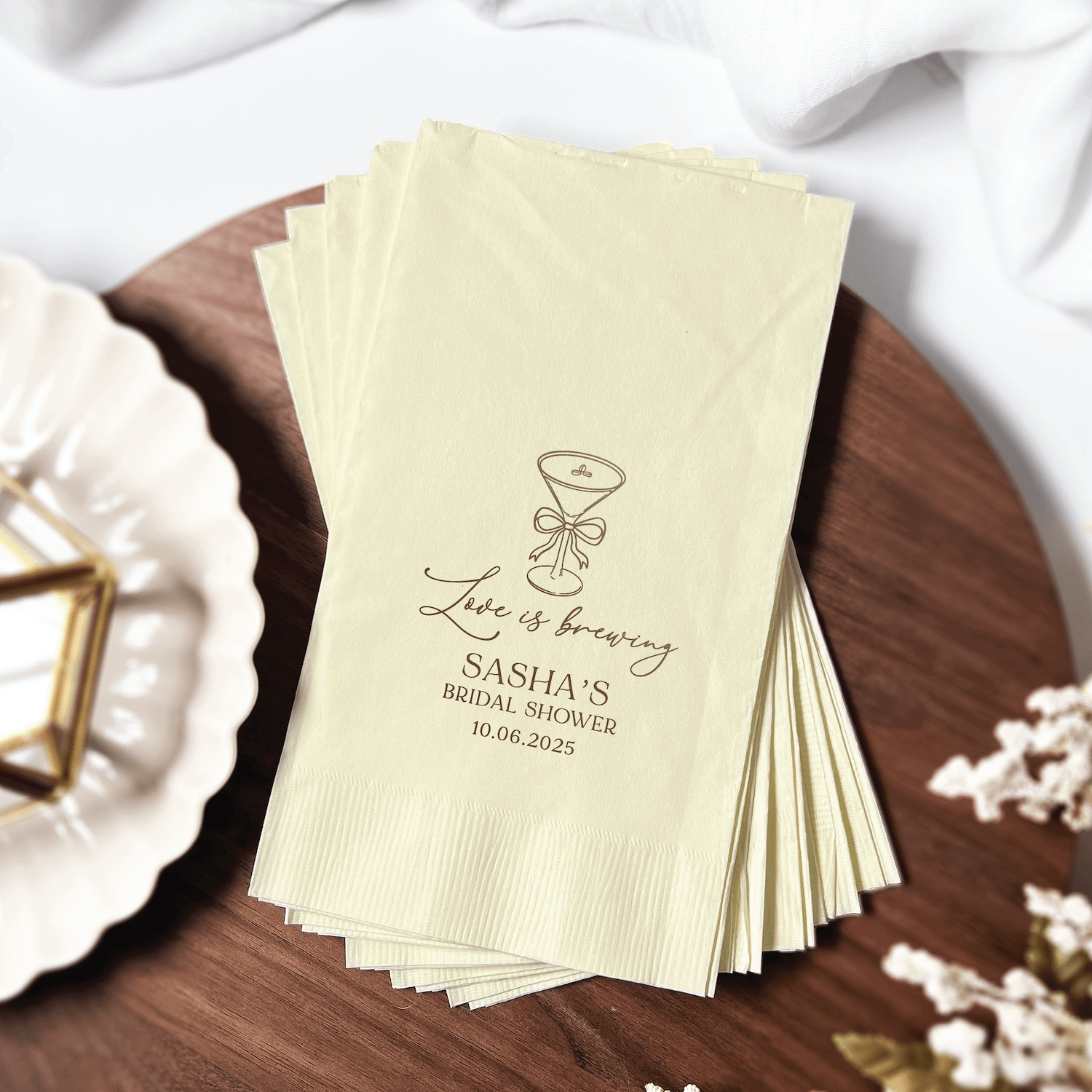 Stack of cream napkins with gold foil champagne glass design and "Love is Brewing Sasha's Bridal Shower" personalization text