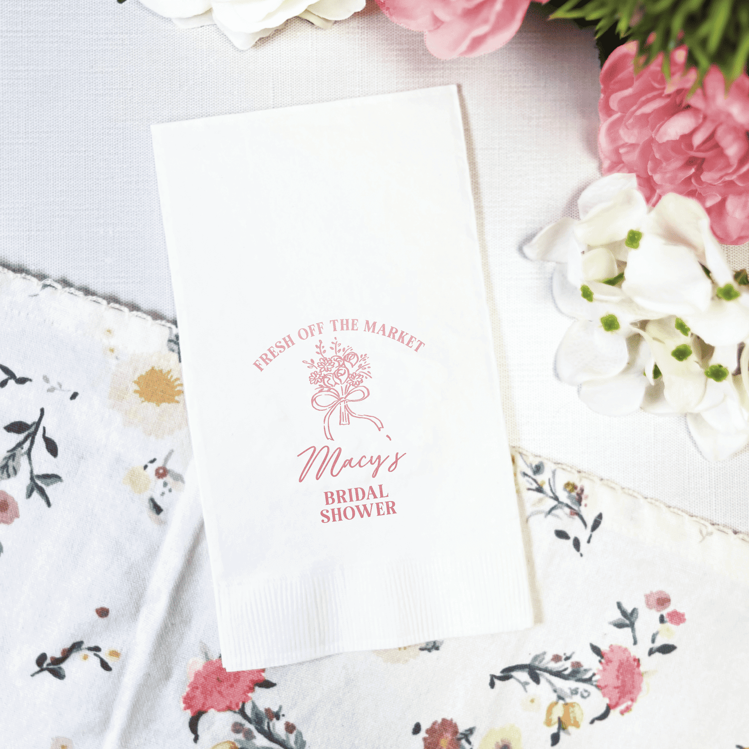 White napkin with pink foil-stamped floral design and "Fresh Off The Market" text for bridal shower