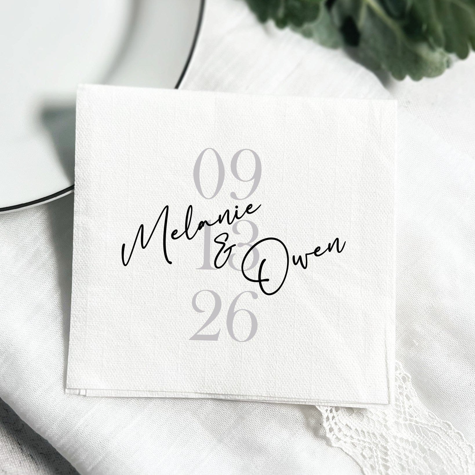 A white textured disposable napkin personalized for a wedding or special event table setting.