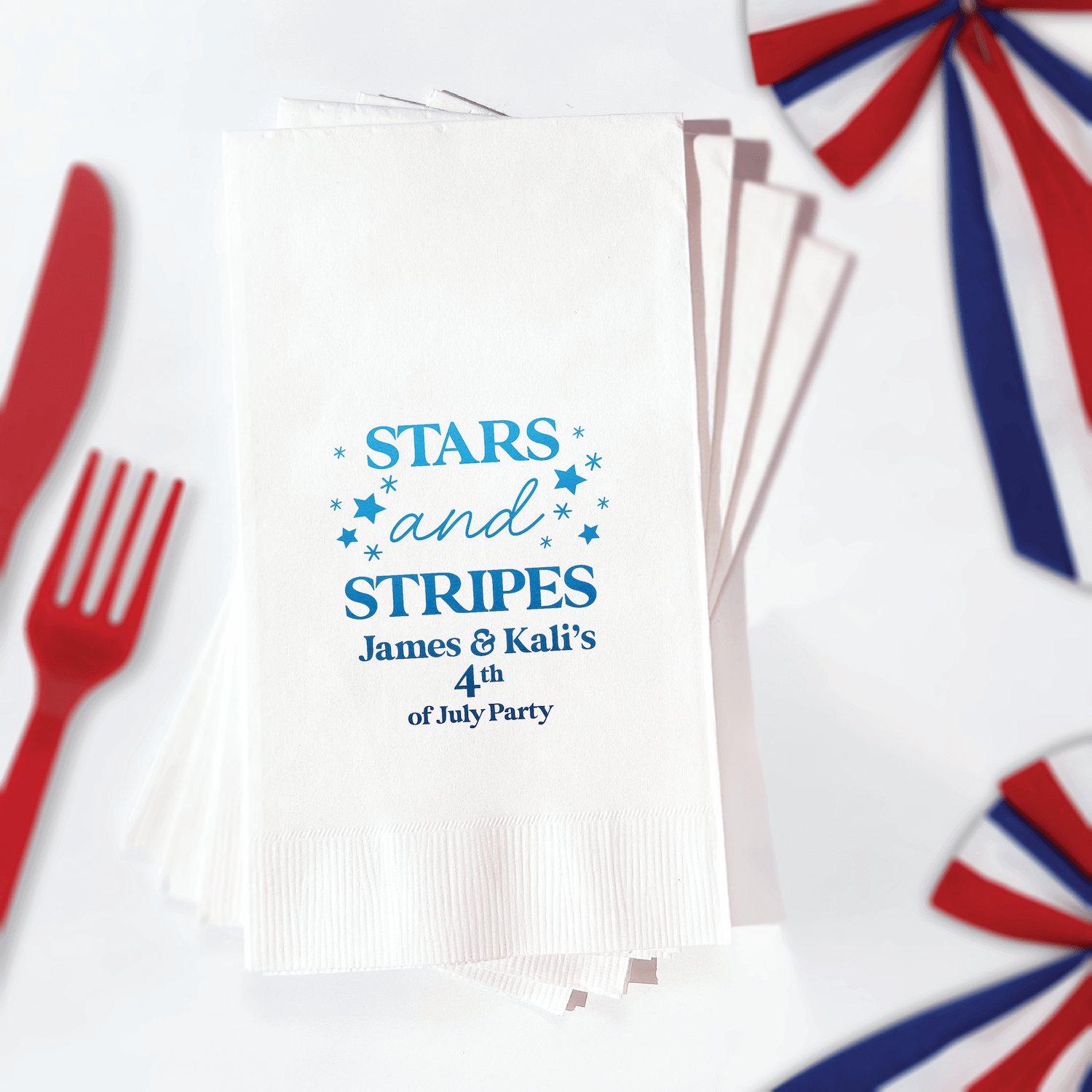 White napkins with blue foil-stamped "Stars and Stripes" design and personalized names for 4th of July party