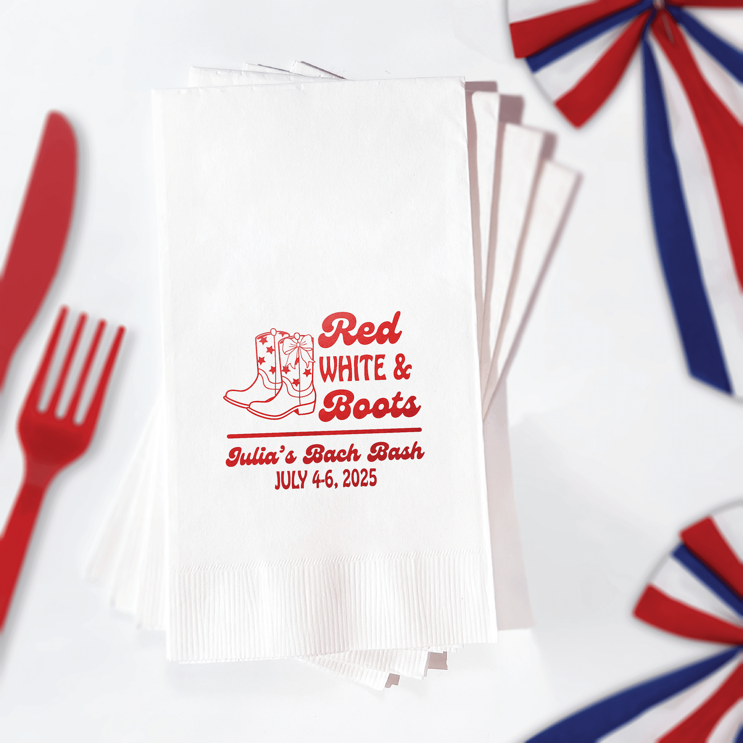 Stack of white napkins with red foil-stamped cowboy boot design and "Red White & Boots" text personalized with "Julie's Bach Bash July 4-6, 2025"