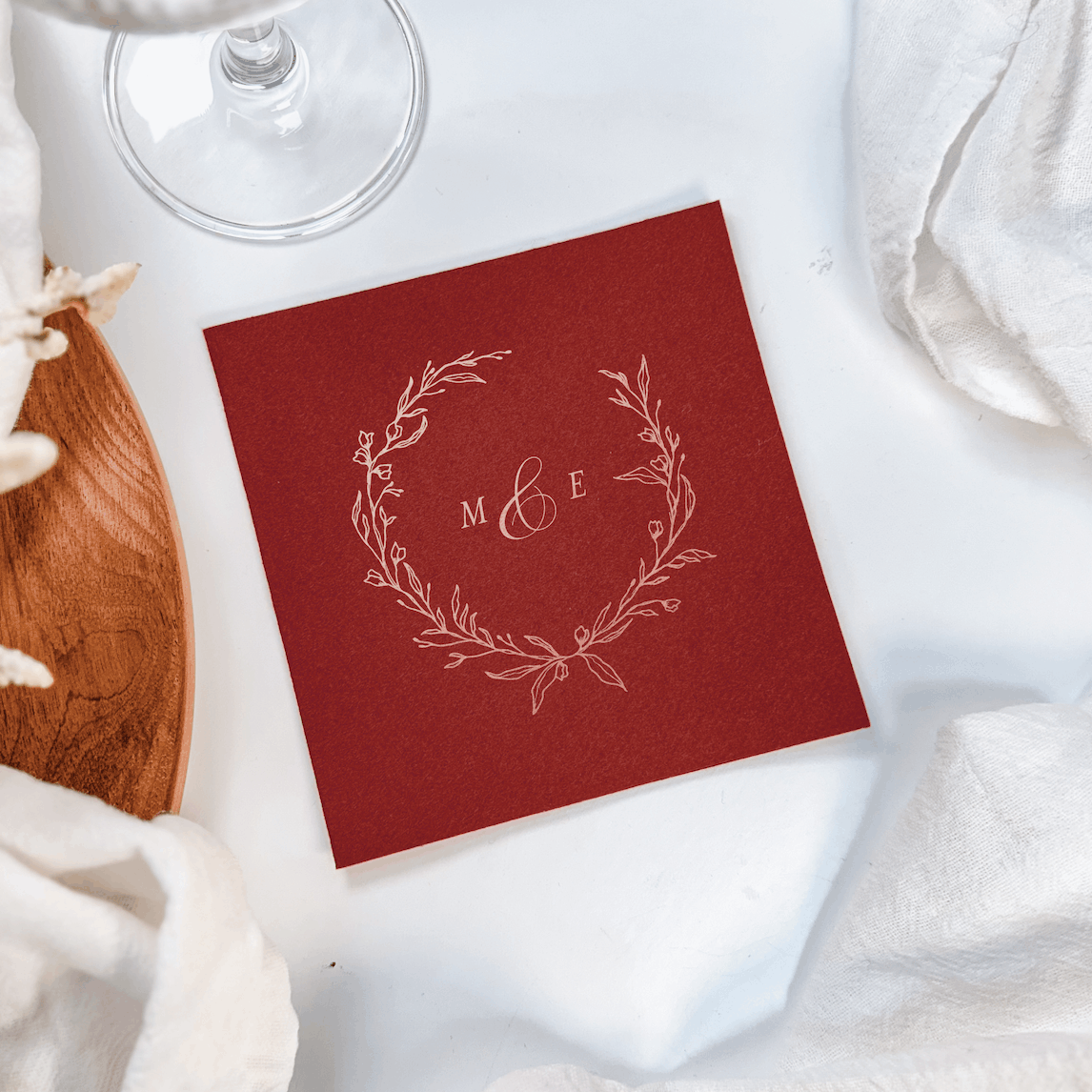 Red cocktail napkin with silver monogram "M" and "E" inside delicate wreath design