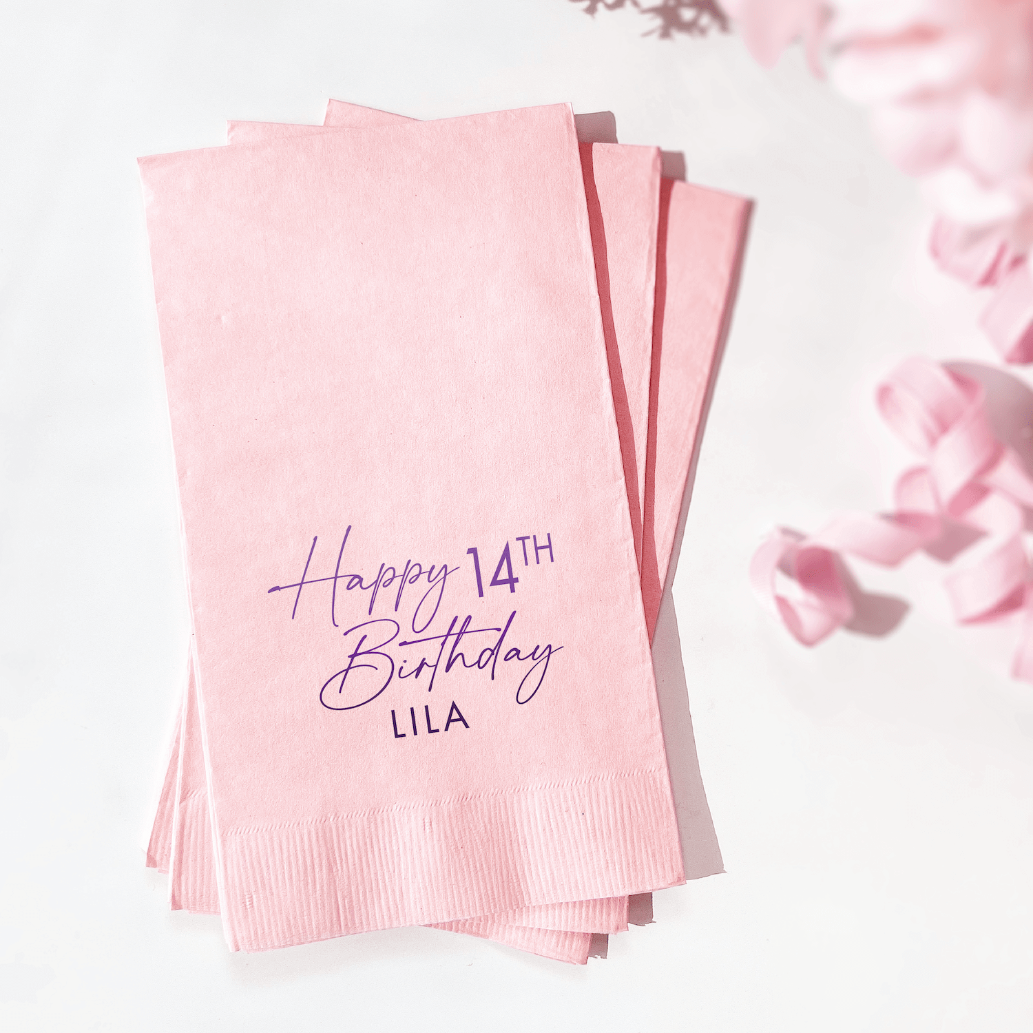 Stack of pink napkins with purple foil stamped text reading "Happy 14th Birthday LILA"