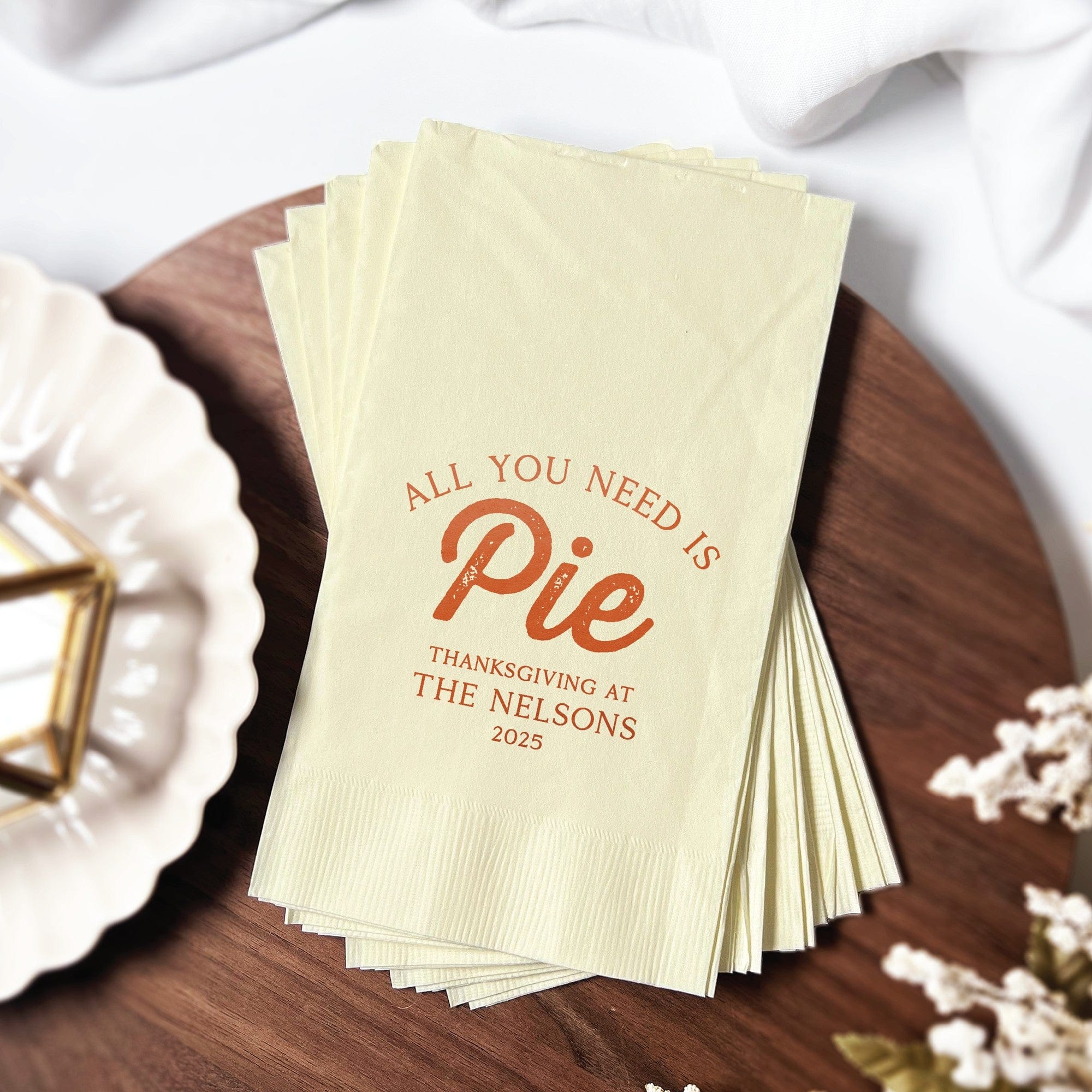 A stack of light-colored rectangular paper napkins with a custom orange print, suitable for a Thanksgiving event.