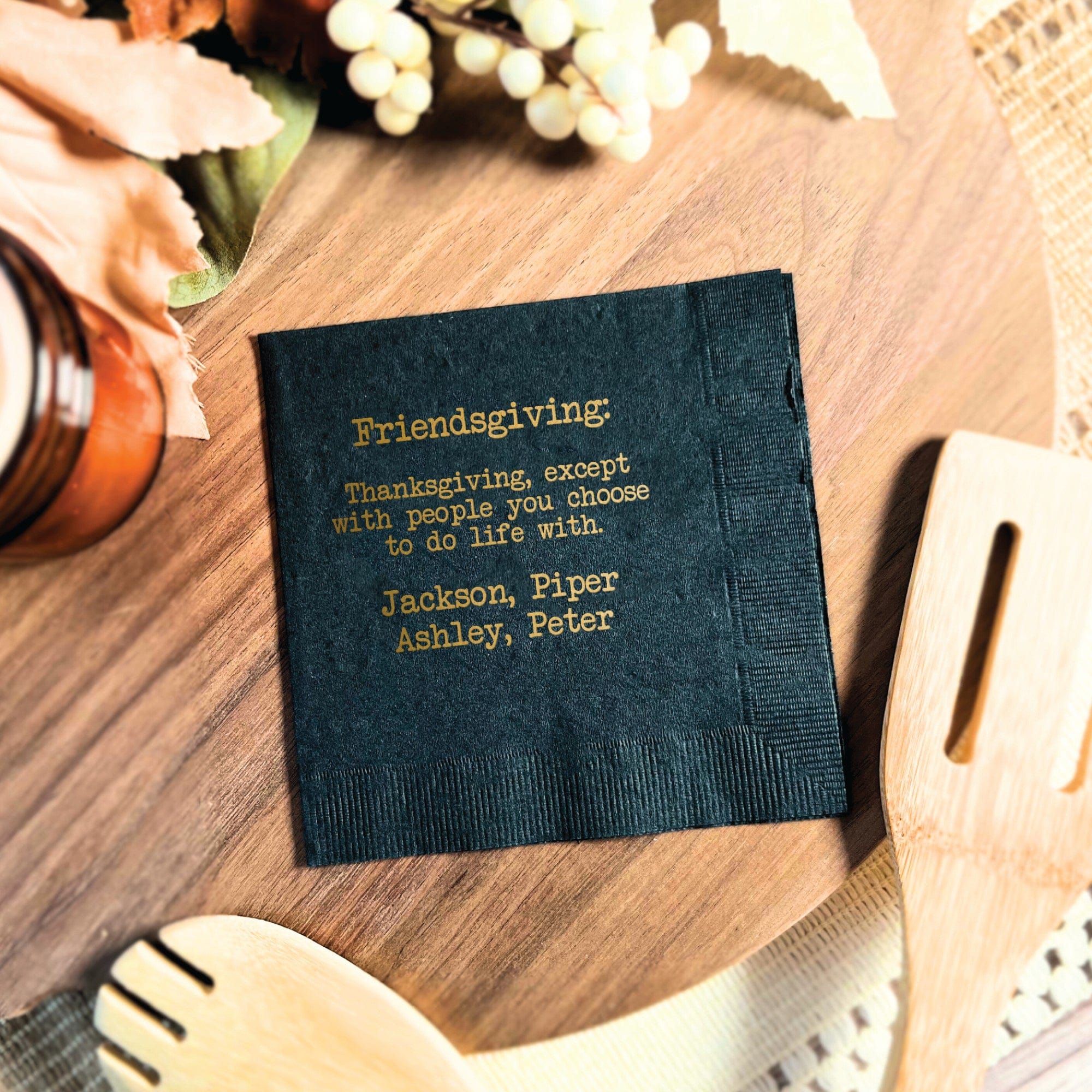 A dark colored personalized paper napkin featuring gold foil printing, ideal for a Friendsgiving celebration.