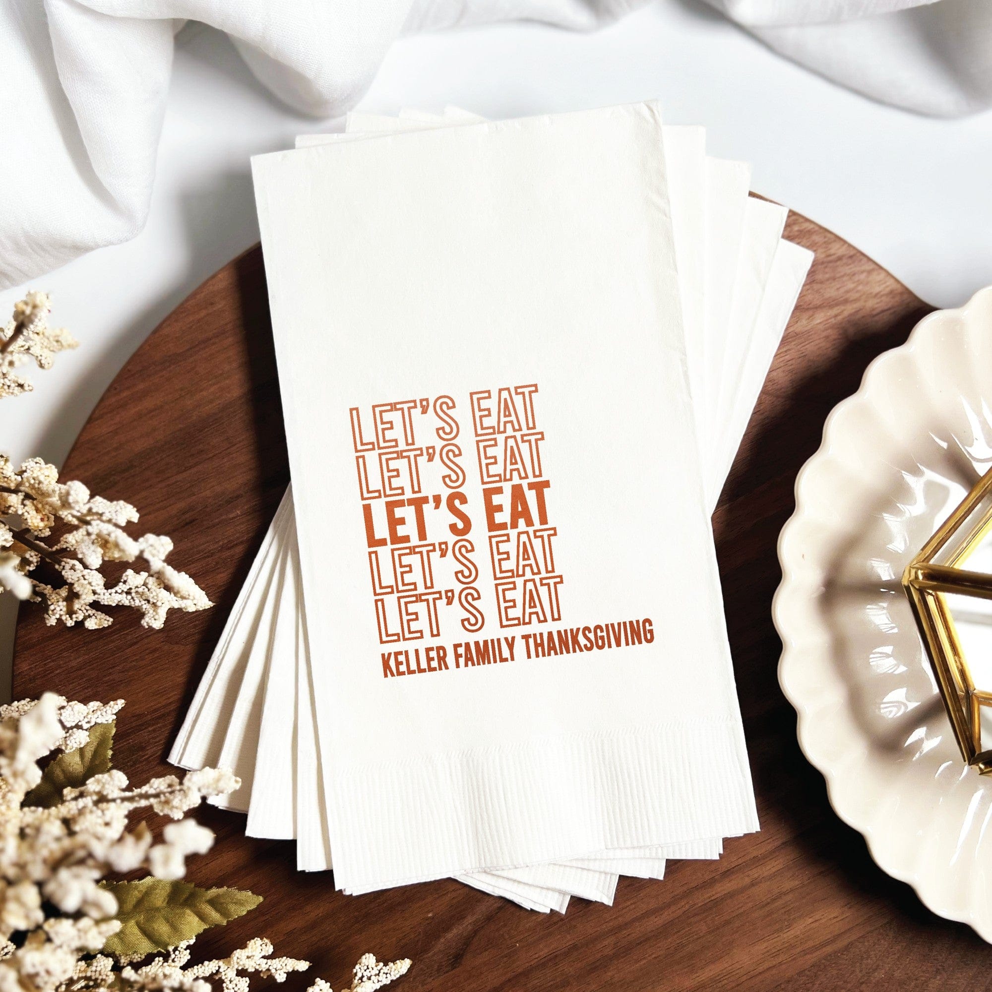 A stack of white disposable paper napkins personalized for a holiday event.