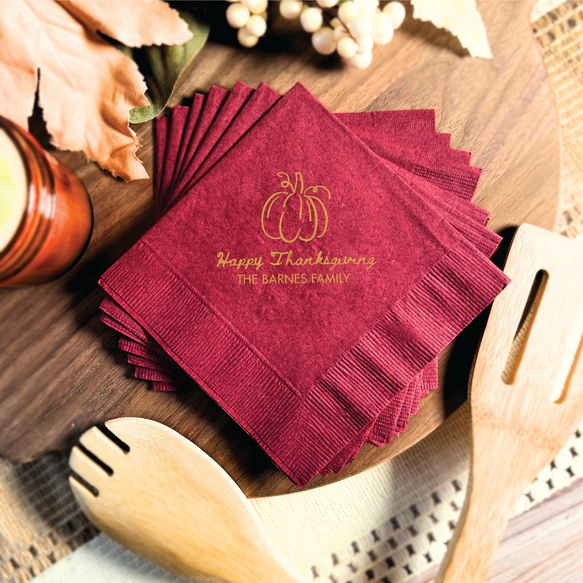 A stack of maroon, personalized paper napkins with a textured finish, featuring a pumpkin design ideal for a fall celebration.