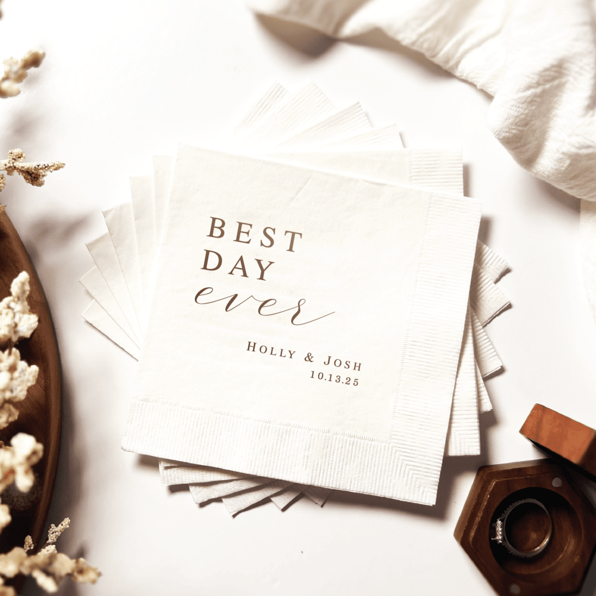 Cream napkins with "Best Day Ever" text and personalized names "Holly & Josh" with date 10.22.23 in gold foil stamping
