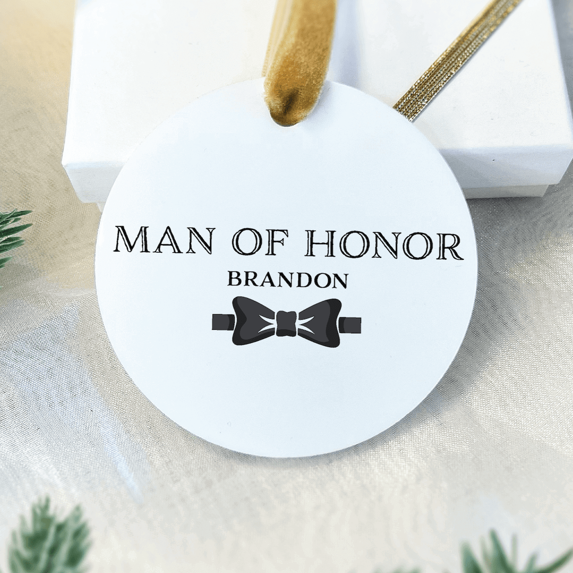 White acrylic ornament with "Man of Honor Brandon" text and black bow tie design, gold string hanger