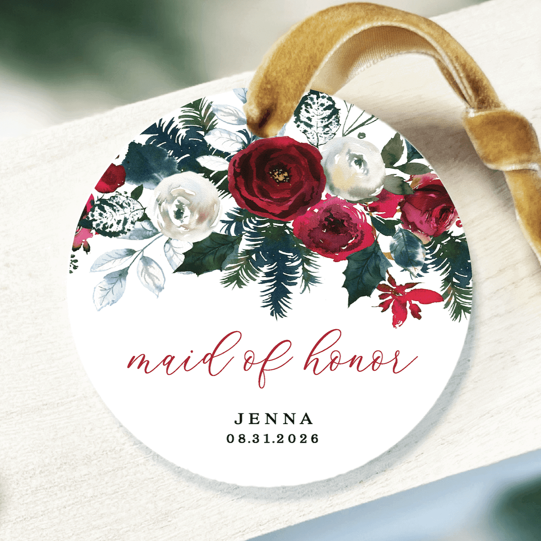 White acrylic ornament with gold ribbon, featuring red and white florals, "maid of honor" script text, and personalized name and date.