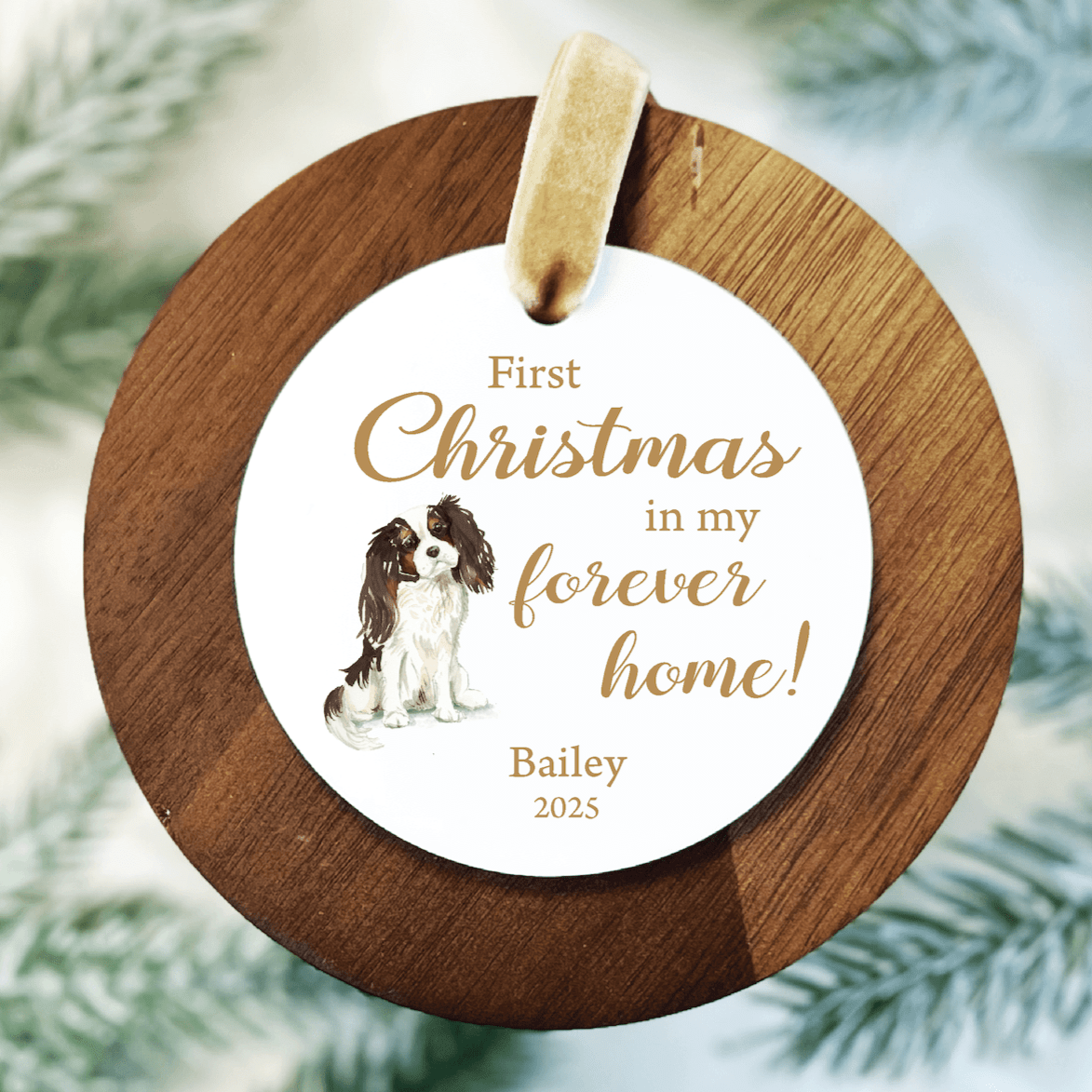 Wooden circular ornament with white center medallion featuring brown spaniel dog, gold text reading "First Christmas in my forever home" and personalized name "Bailey" with 2025 date.