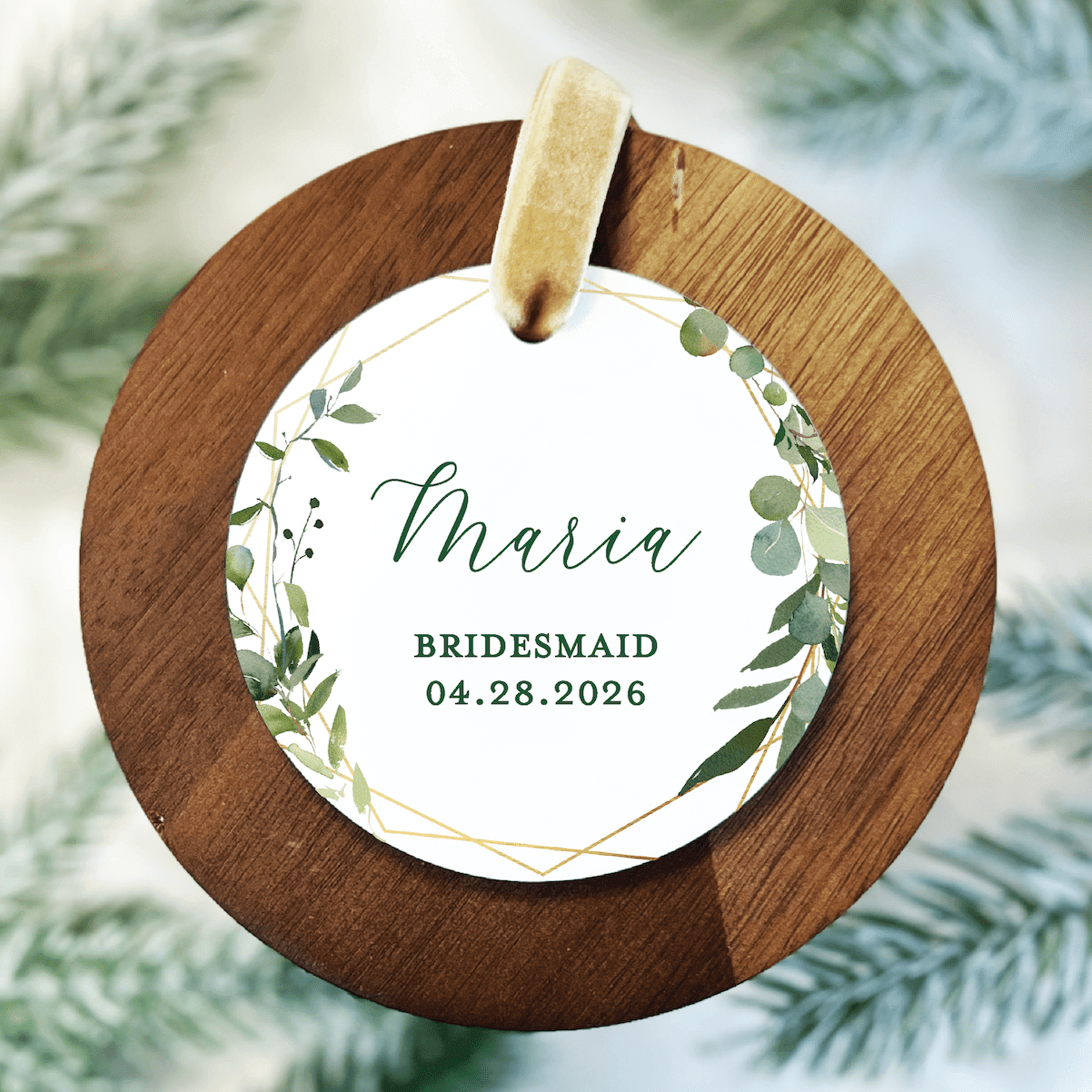 Round wooden ornament with white acrylic center featuring green leaf design, personalized with "Merie" and "BRIDESMAID 04.28.2026"