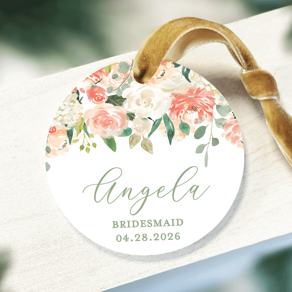 White acrylic ornament with gold ribbon featuring personalized name Angela, bridesmaid role, and wedding date with watercolor floral design.