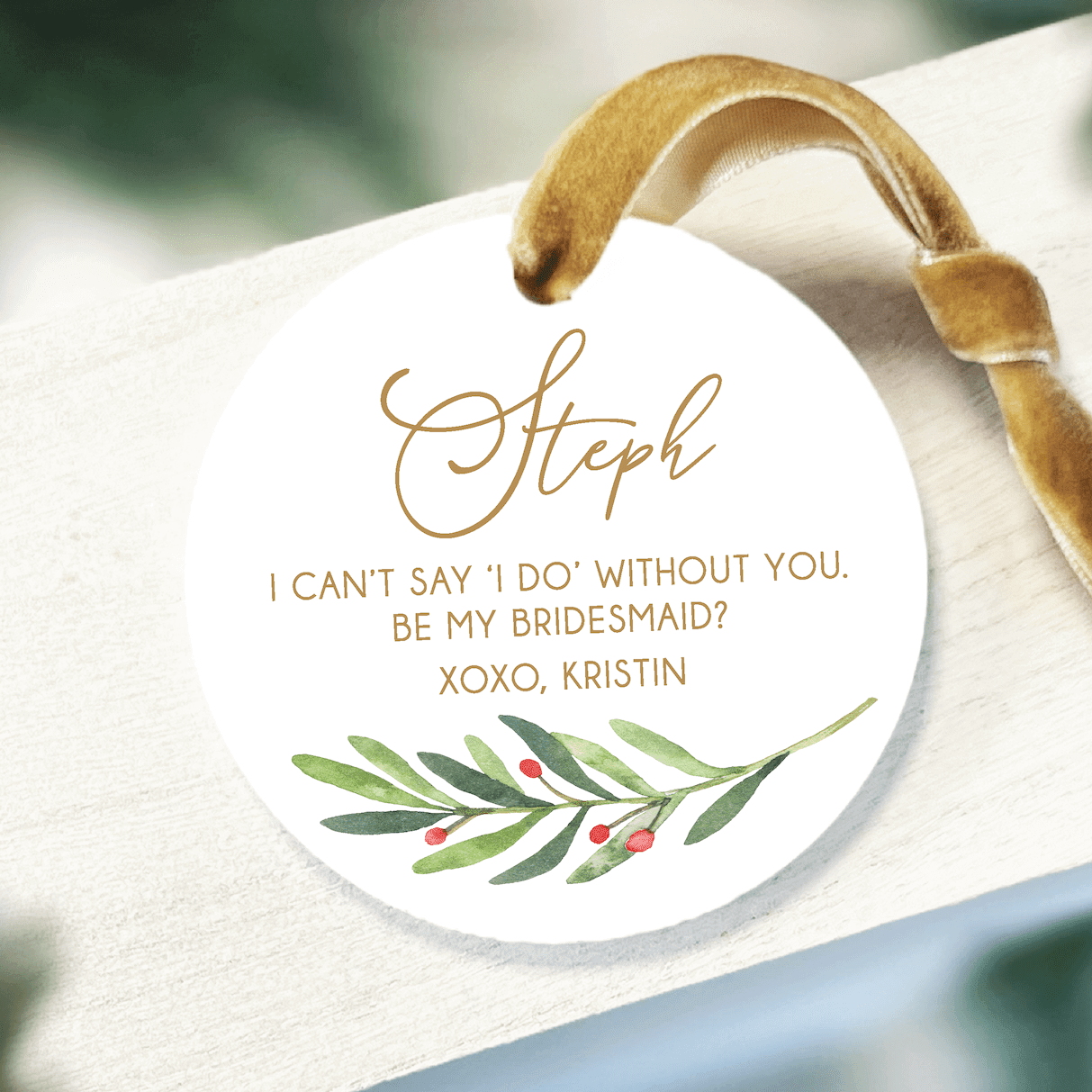 White round acrylic ornament with gold script text reading "Steph" and personalized bridesmaid proposal message with watercolor olive branch design and tan ribbon loop.