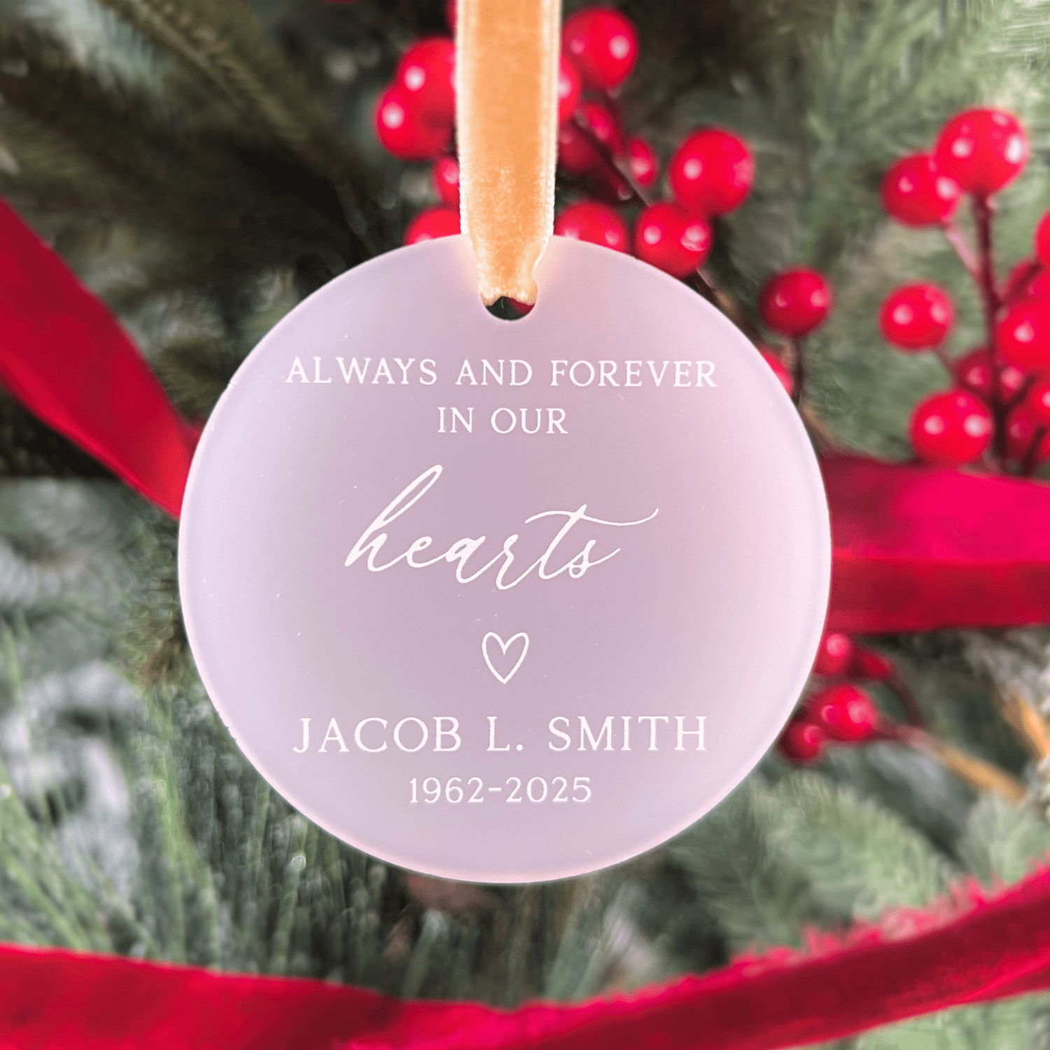 Frosted acrylic memorial ornament with "Always and Forever in Our Hearts" text, personalized name and dates, small heart symbol, hanging from peach ribbon.